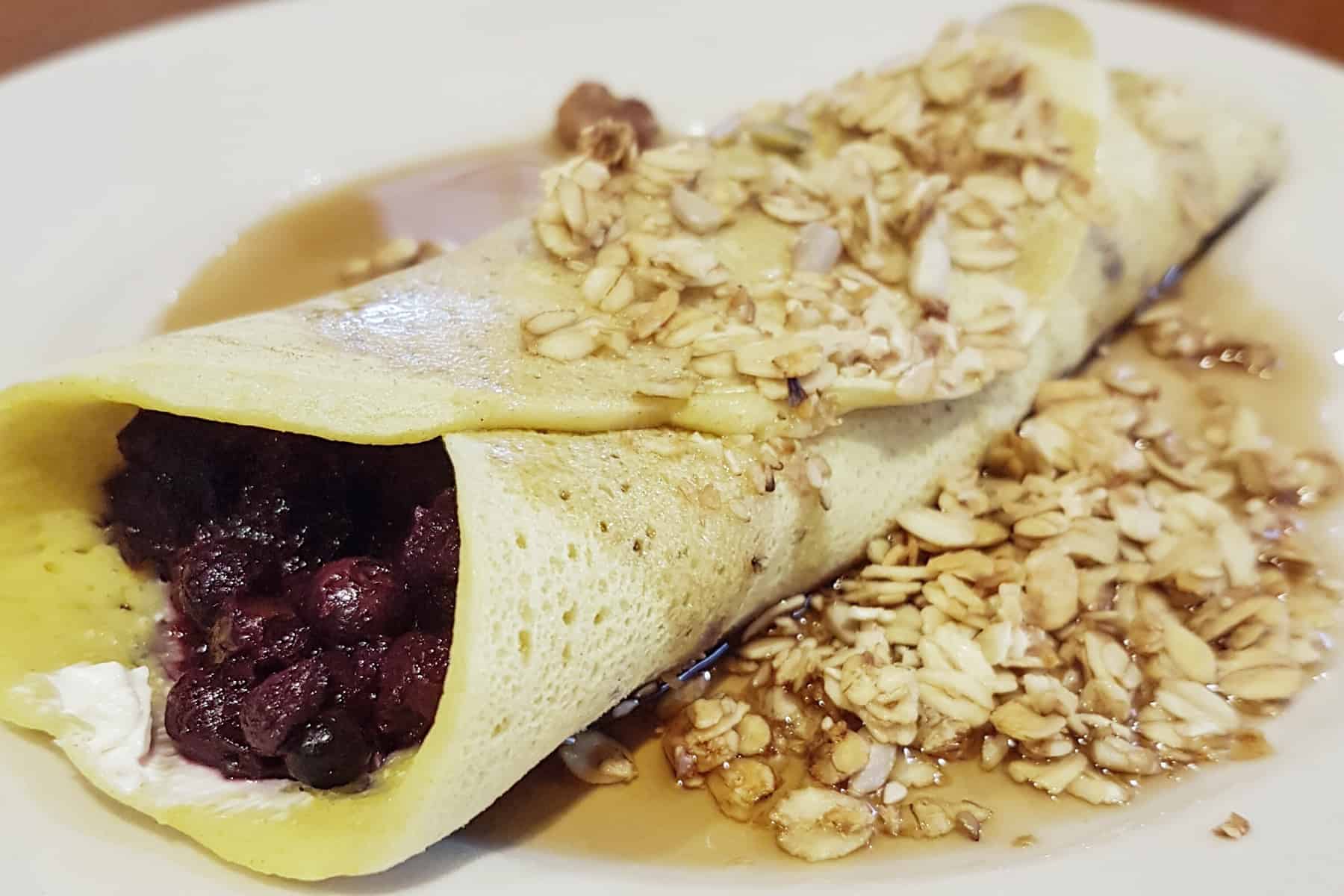 A ployes buckwheat pancake filled with jammy blueberries and yoghurt and topped with granola.