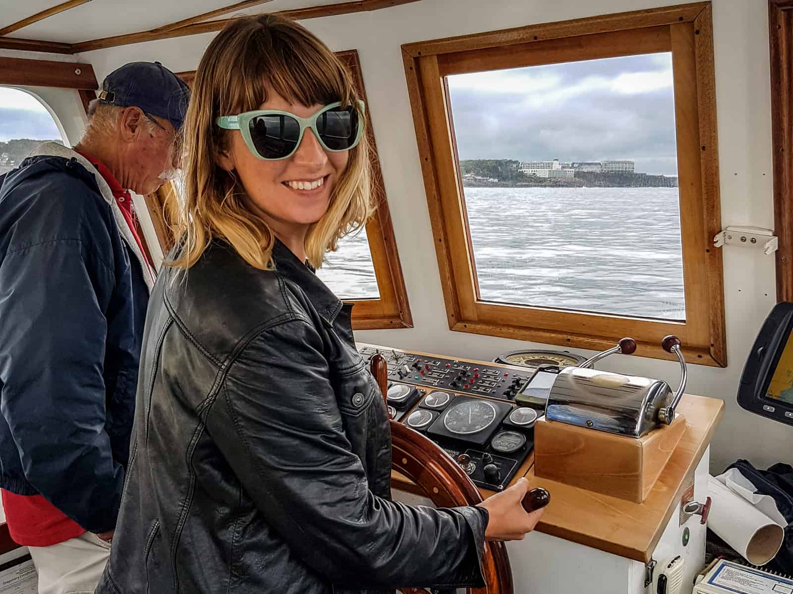 A blonde woman steers a small wooden boat while out at sea in Ogunquit, Maine. 