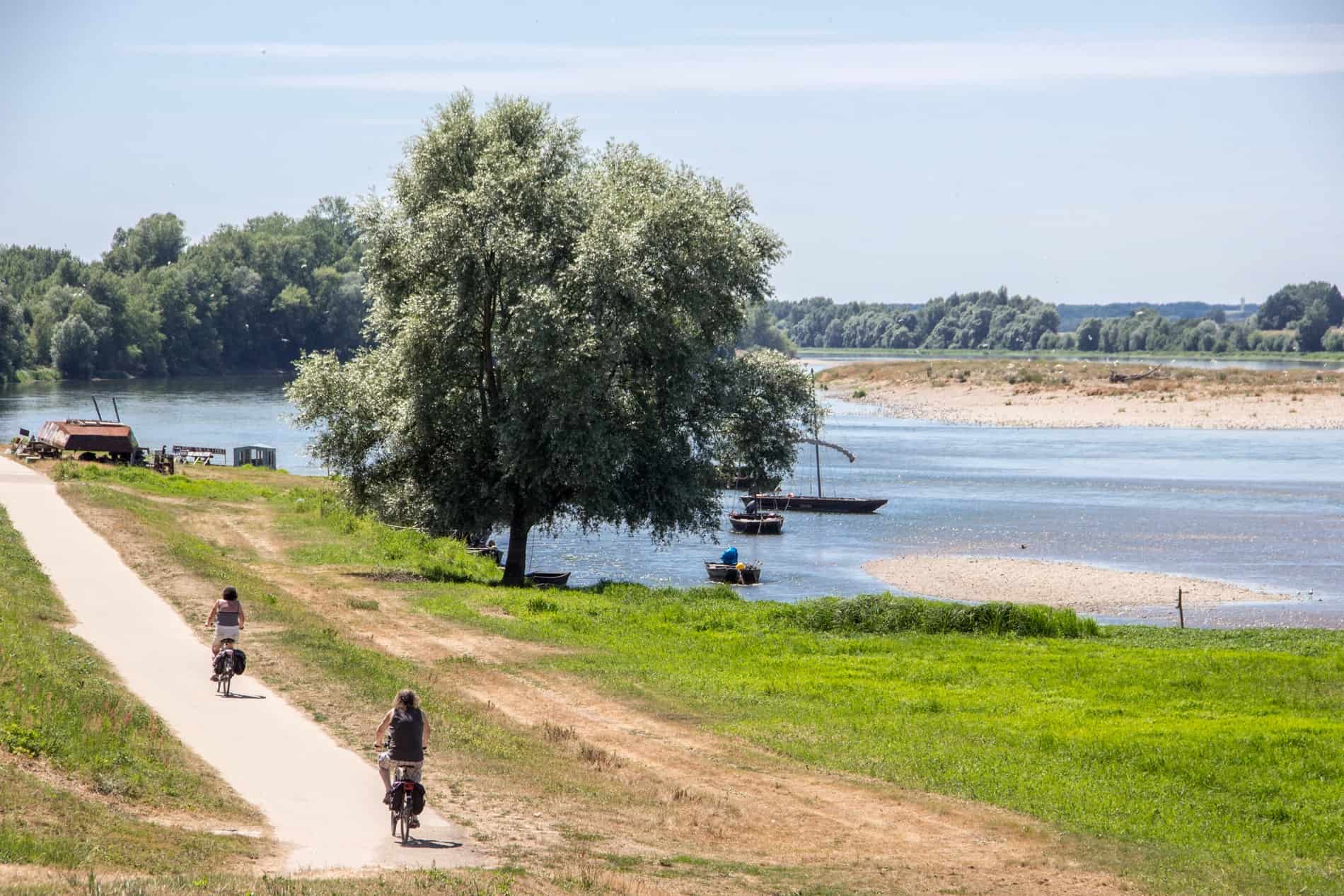 Two people biking in the Loire Valley, France alongside the river.