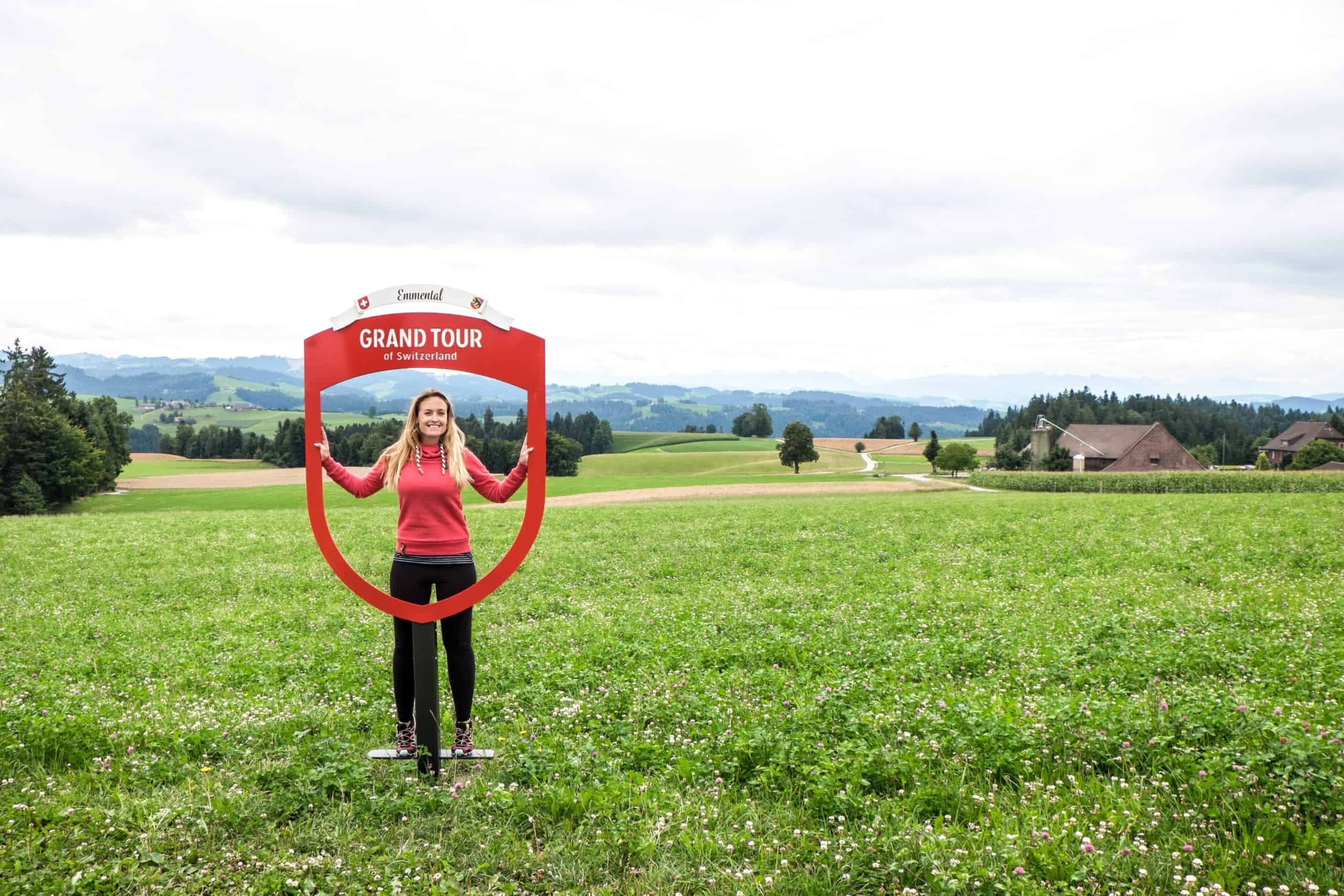 A woman stands at a Grand Tour of Switzerland sign in the Visiting the Emmental Valley in Bern