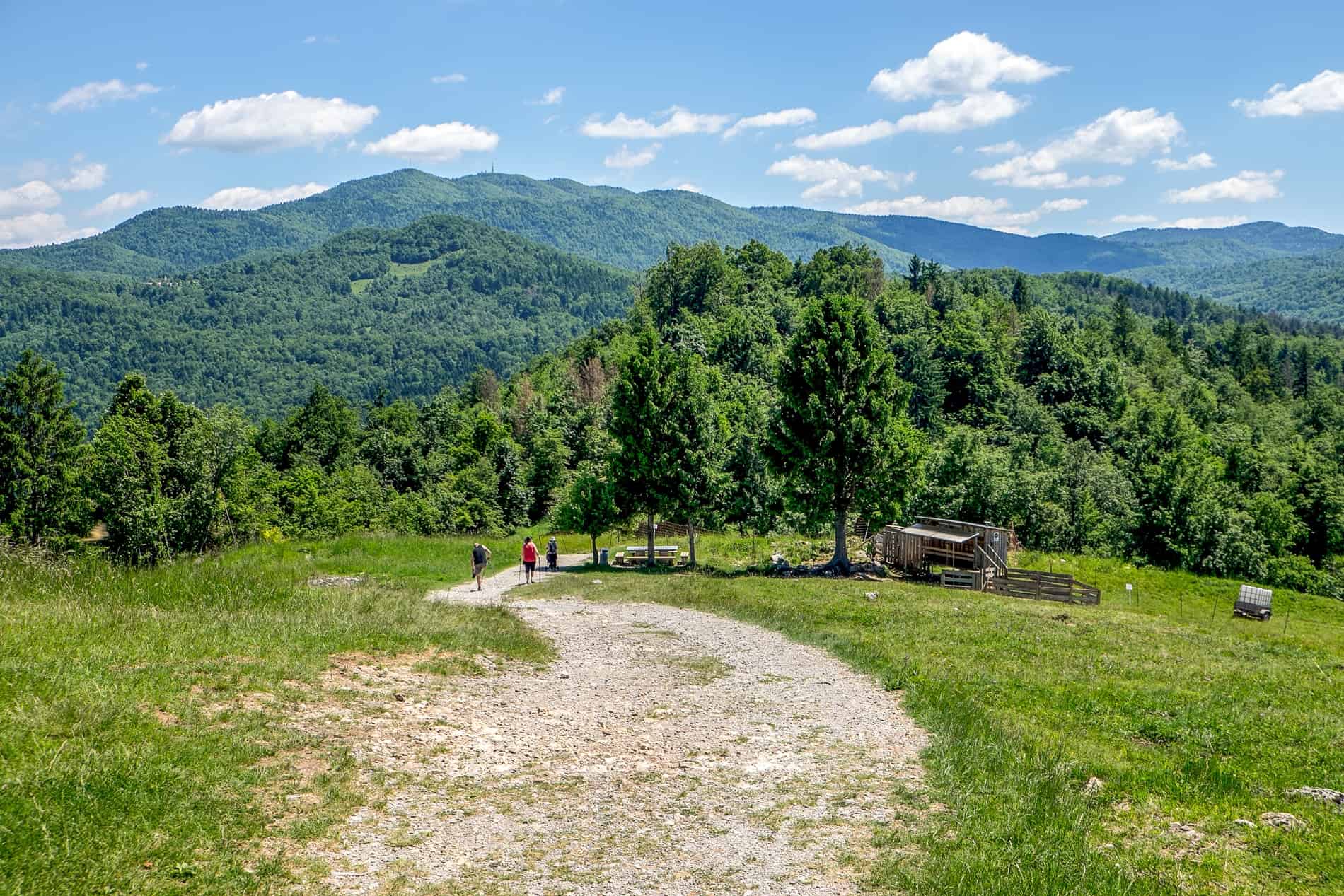 Hikers climbing the mountain-backed St. Ana Hill at Podpec Lake, Slovenia.