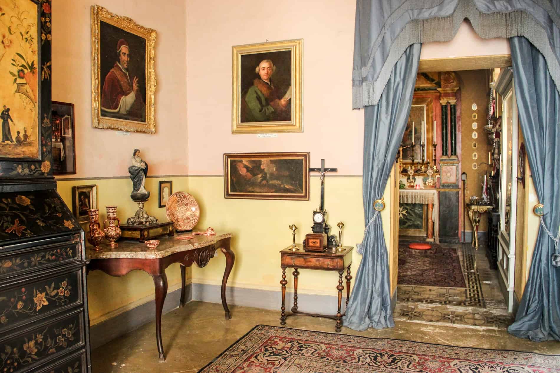 Opulent wooden furnishing, oil paintings and light blue door drapes in the noble house of Casa Rocca Piccola in Malta.