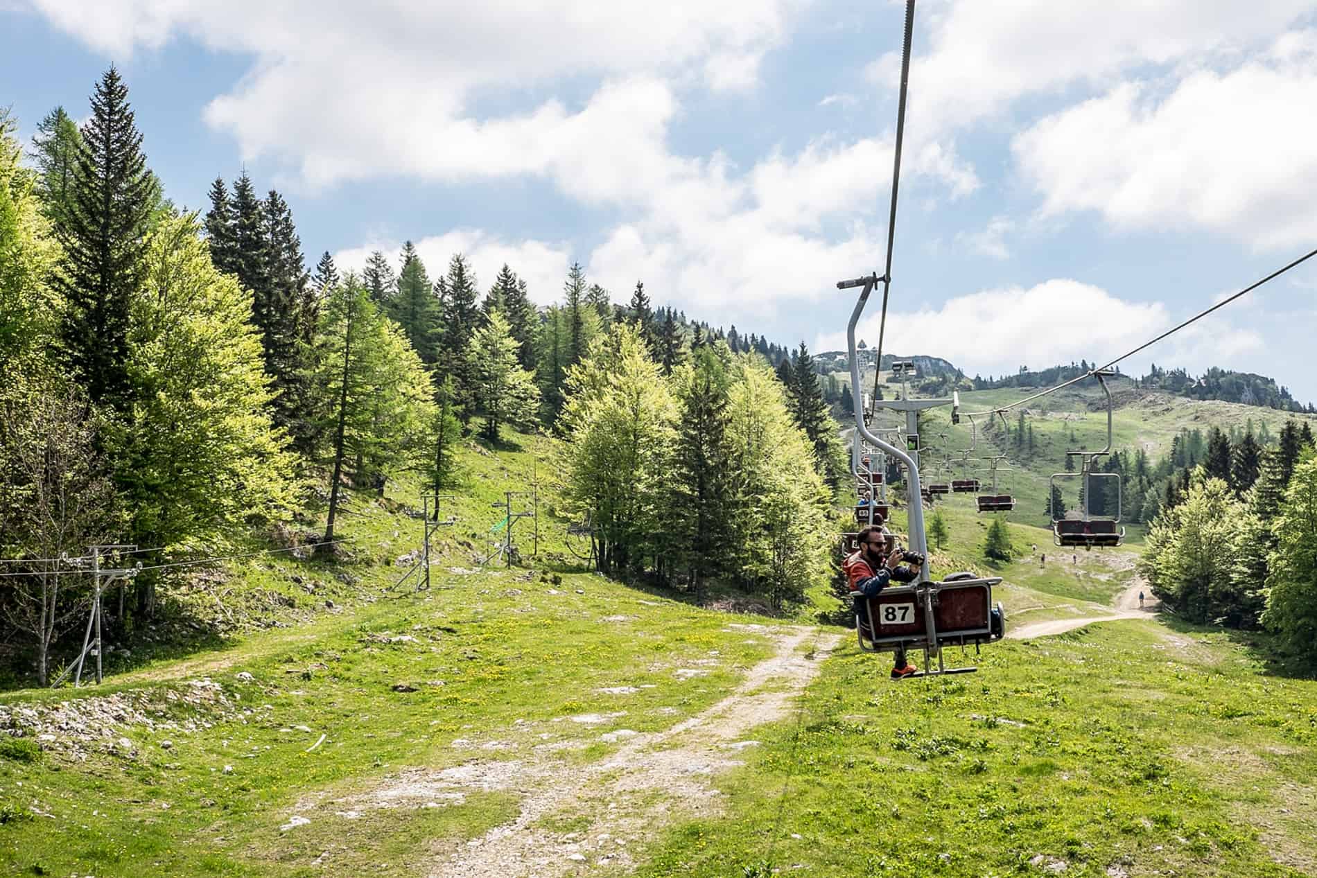 A man filming from the seat of the cable car going up to the forested Kamnik Alps in Slovenia. 