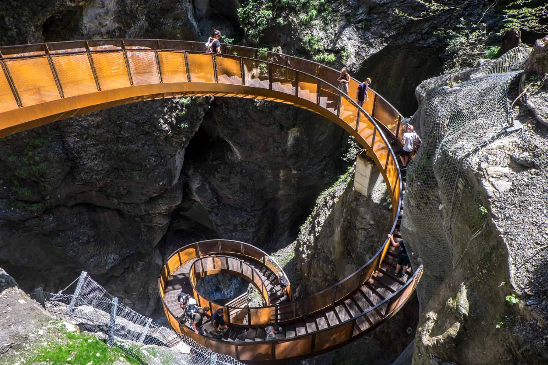 People walking down the copper coloured winding 'helix' staircase in the natural gorge called Liechtensteinklamm in Austria