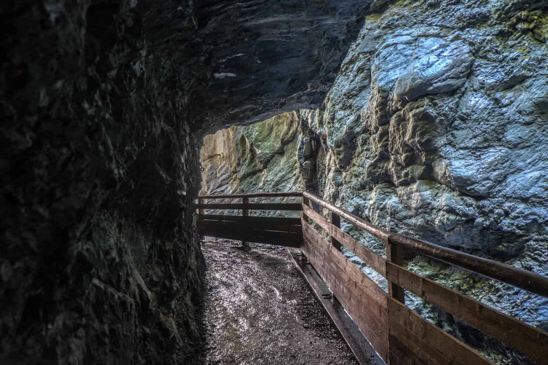 A pathway marked by a wooden barrier rail curves to the left through the narrow Liechtensteinklamm gorge