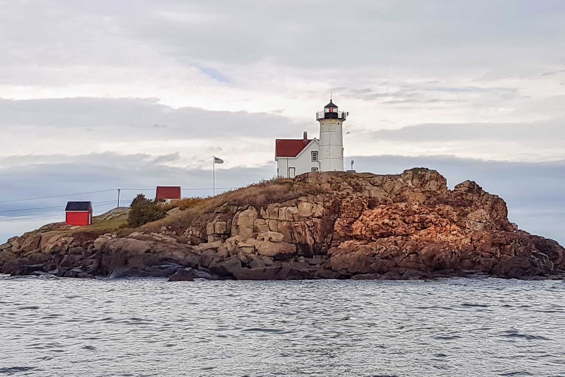 The small Nubble Lighthouse, built on a tiny mound of land off the rocky coastline of Maine, US 1. 