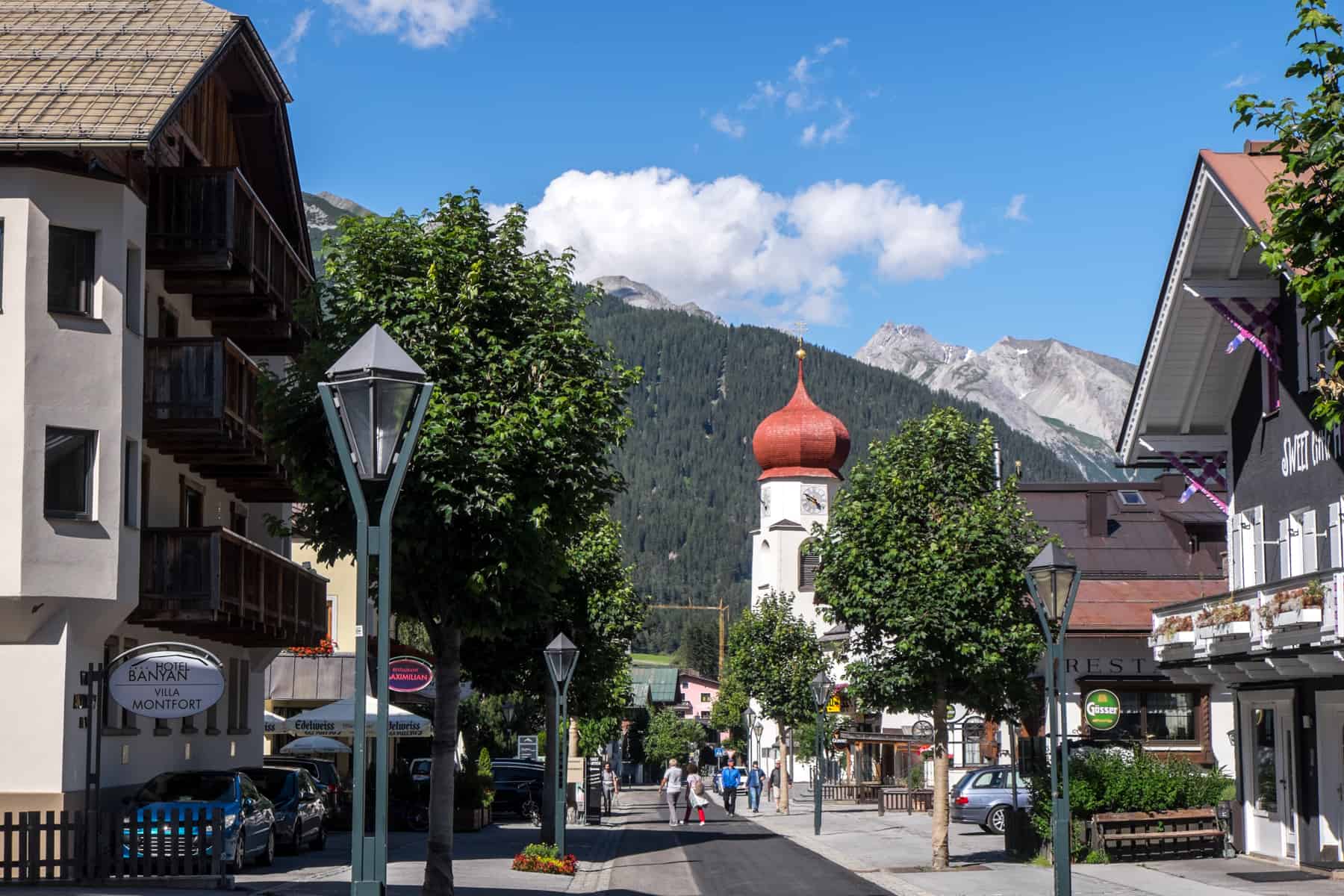 The Red domed roof of the white church in St Anton am Arlberg with the Austrian Alps in the background