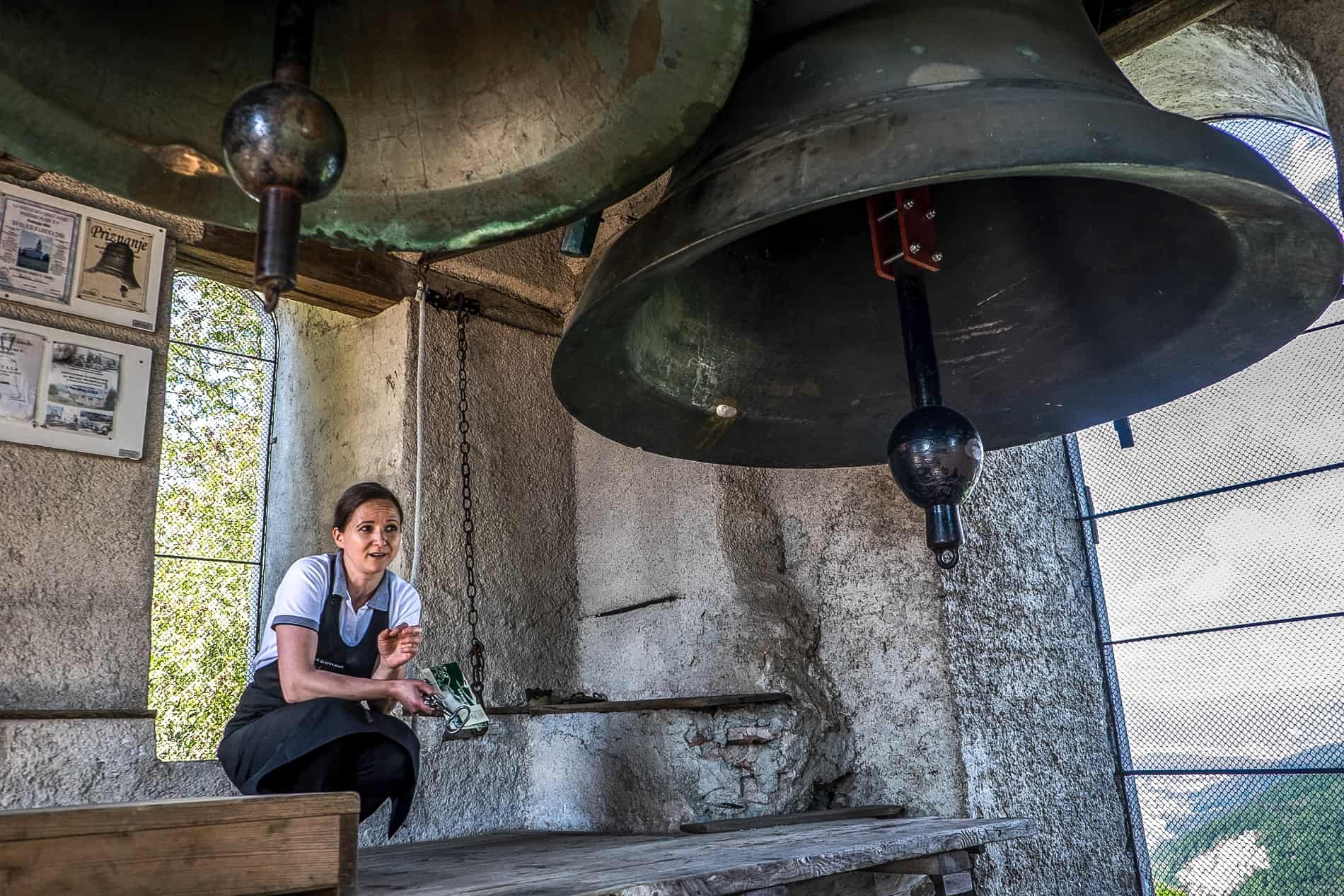A woman crouches next to the Smarna Gora church tower bell in Slovenia.