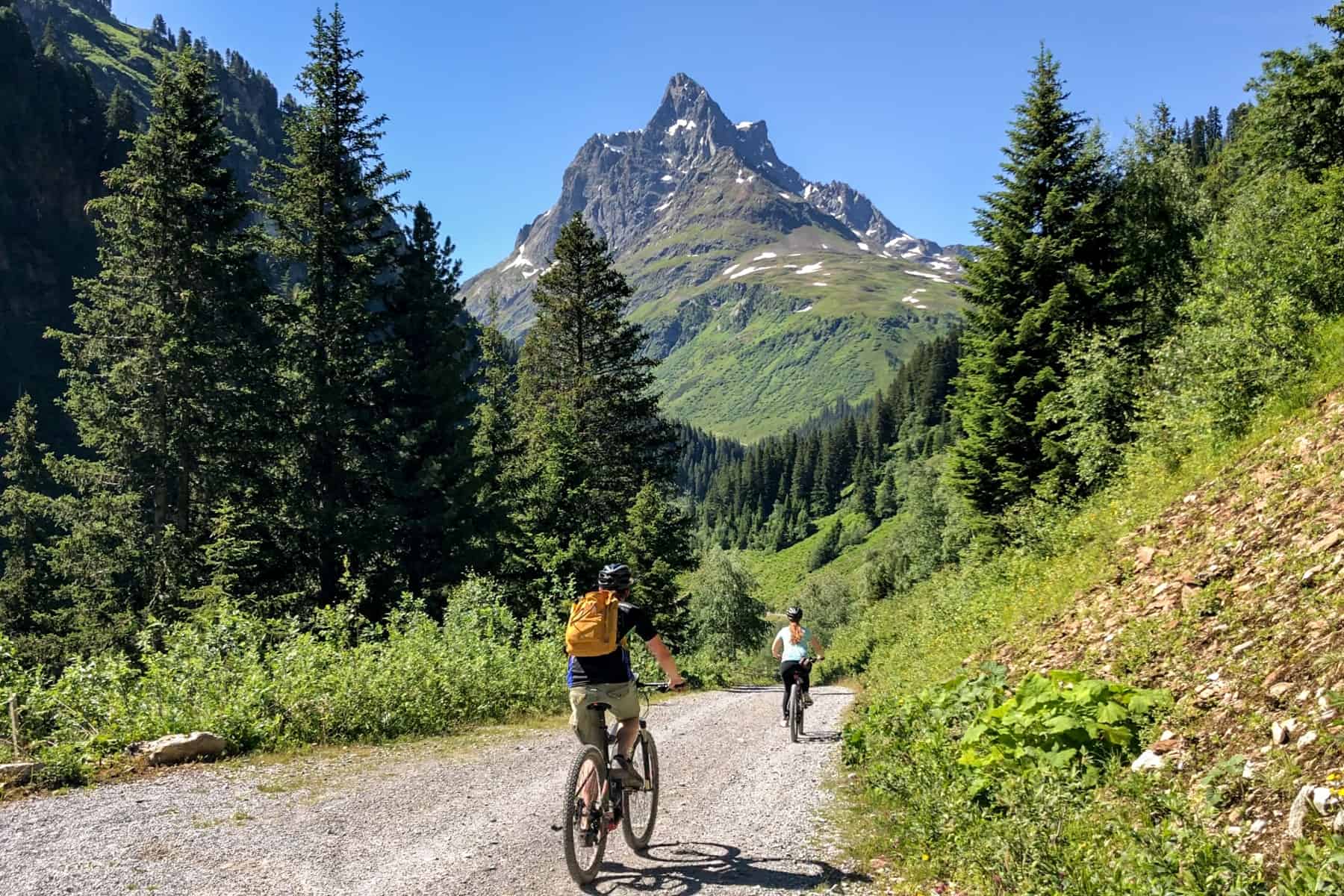 Two people biking on a gravel road towards a mountain in a valley in St. Anton Austria