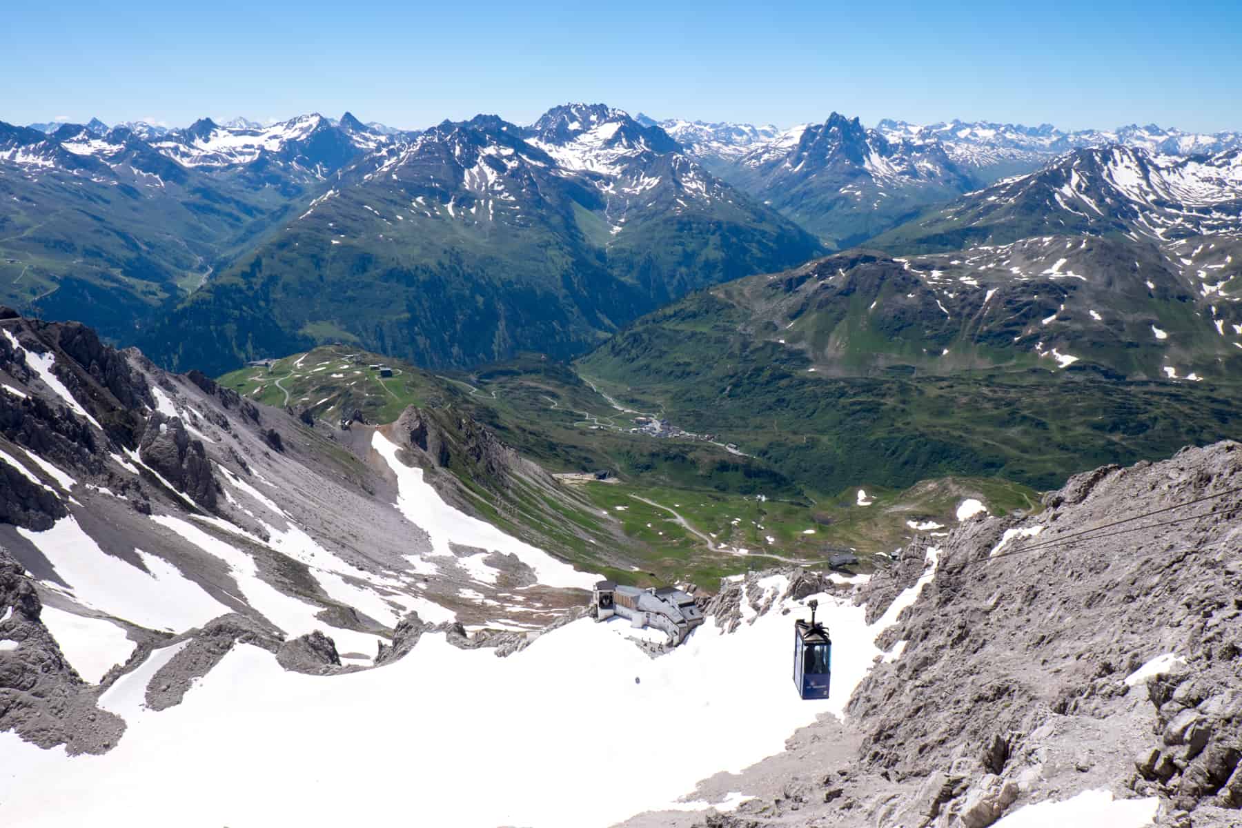 A small, long cable car glides up the highest mountain in St Anton am Arlberg in Austria, still covered in snow in summer