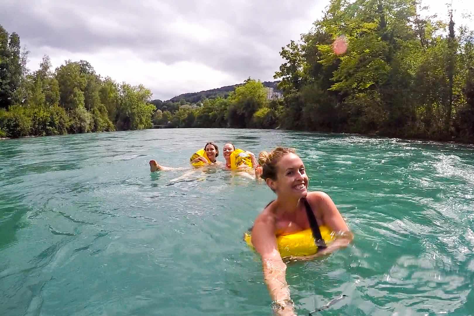 Three women swimming in the clear blue-green Aare River in Bern, Switzerland.