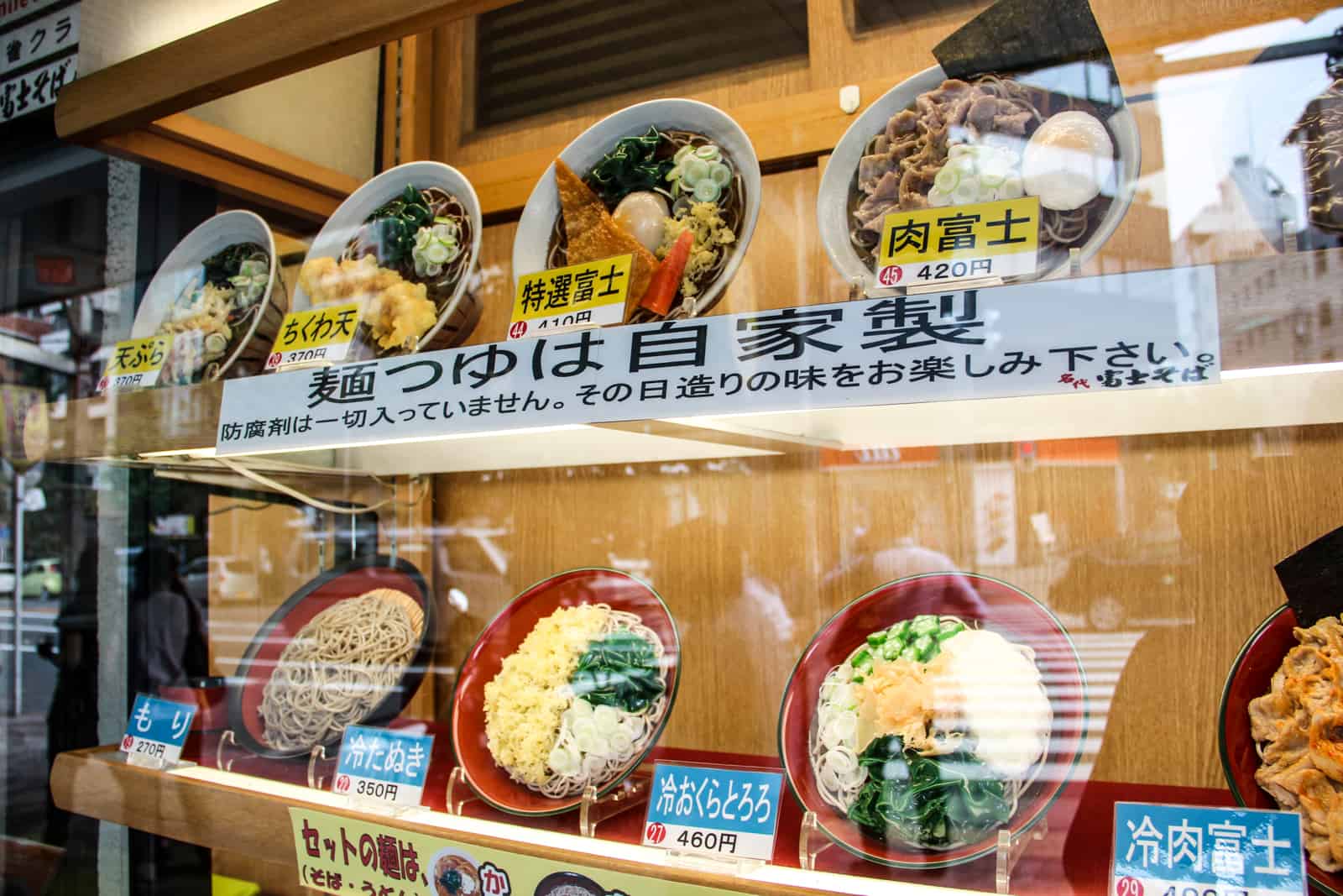 Window display of plastic food dishes at a Japanese restaurant, with price tags. 