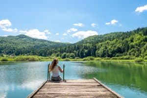 A woman sitting on the wooden jetty of Podpeč Lake near Ljubljana, Slovenia.