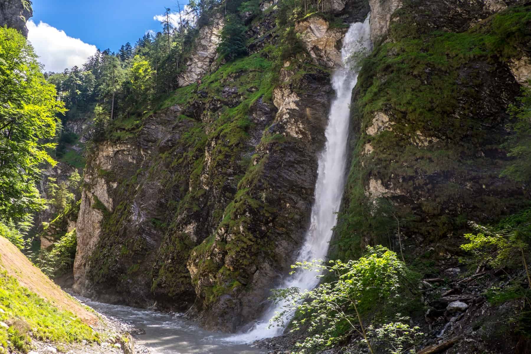 A short white waterfall flows over moss coloured stones at the Liechtensteinklamm gorge in St. Johann in Salzburg