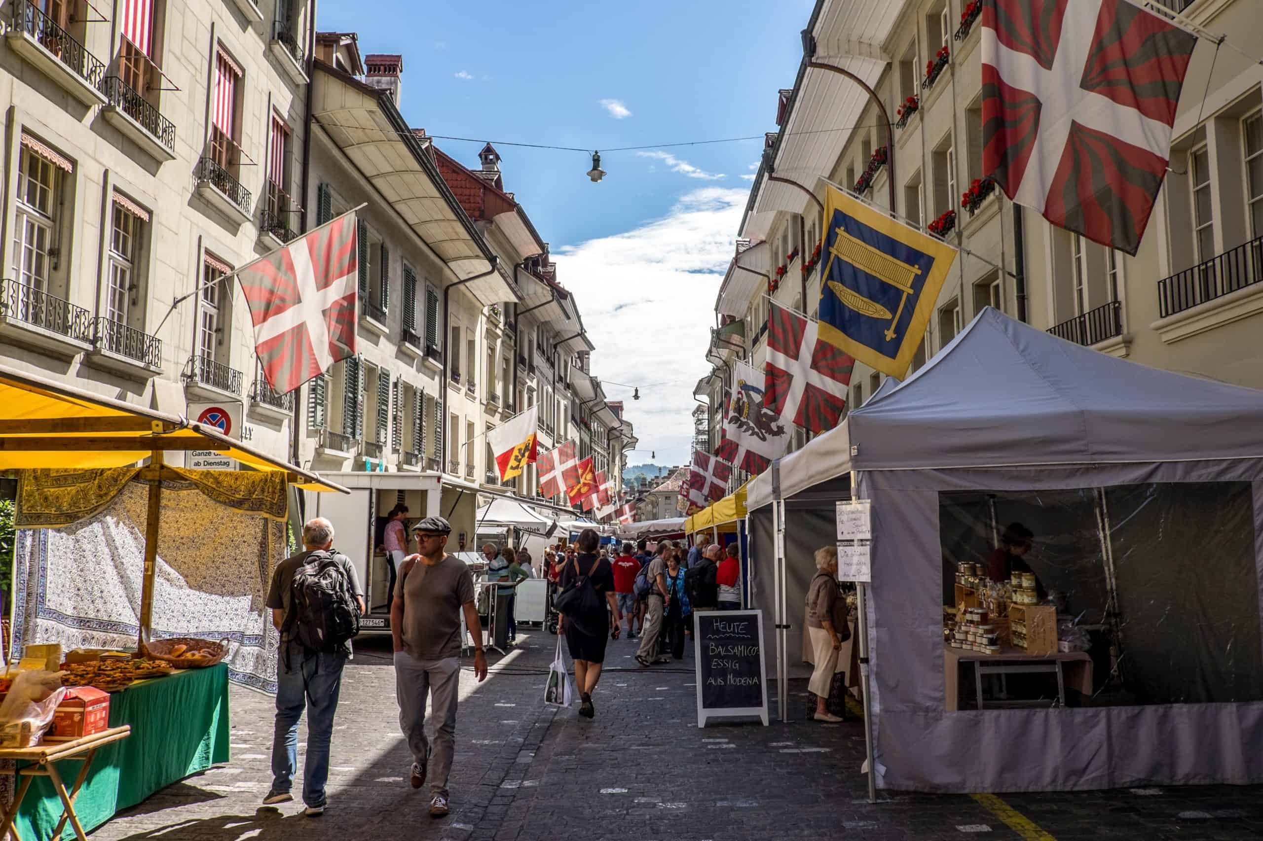 The weekend farmer's market in Bern on a street filed with red and yellow flags