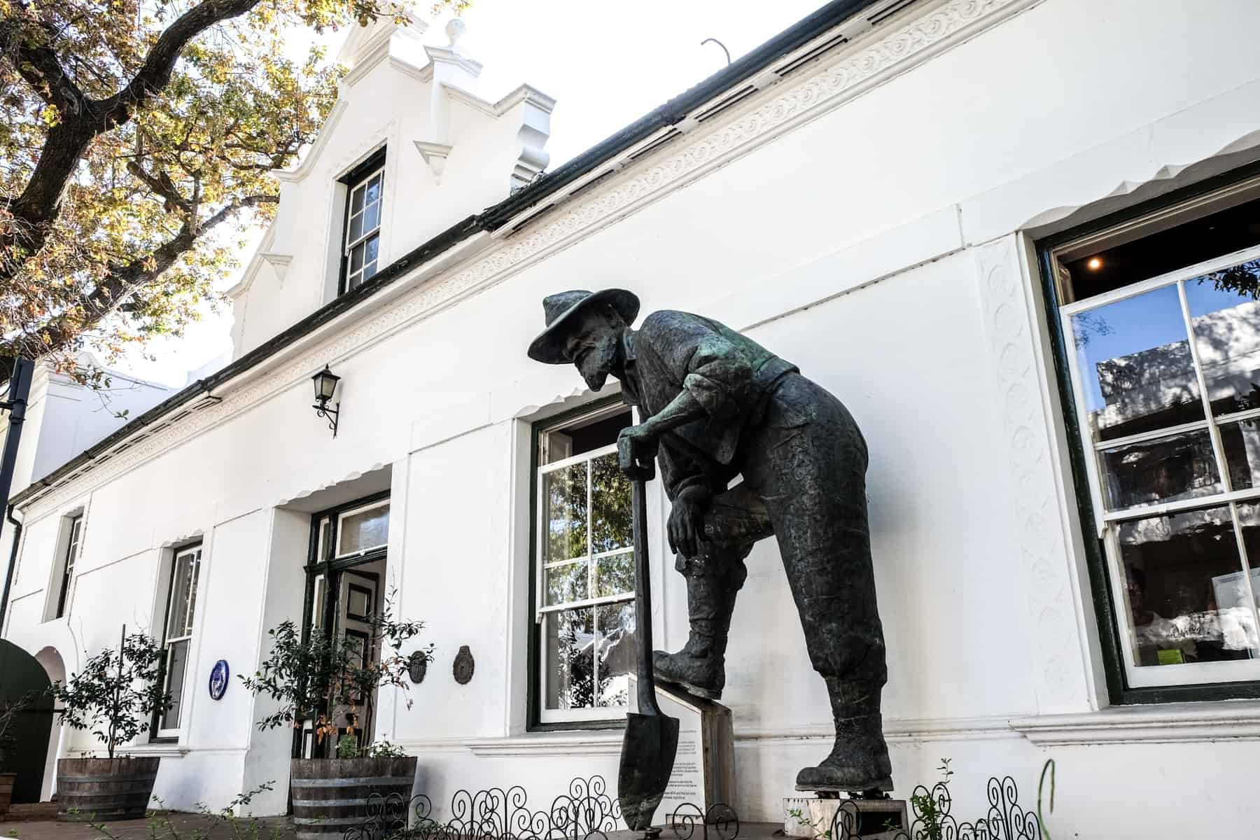 A dark metal art sculpture of a man digging outside a witw building art gallery in Stellenbosch