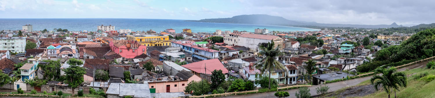 Elevated view over a colourful cluster of buildings of a coastal town in Cuba.