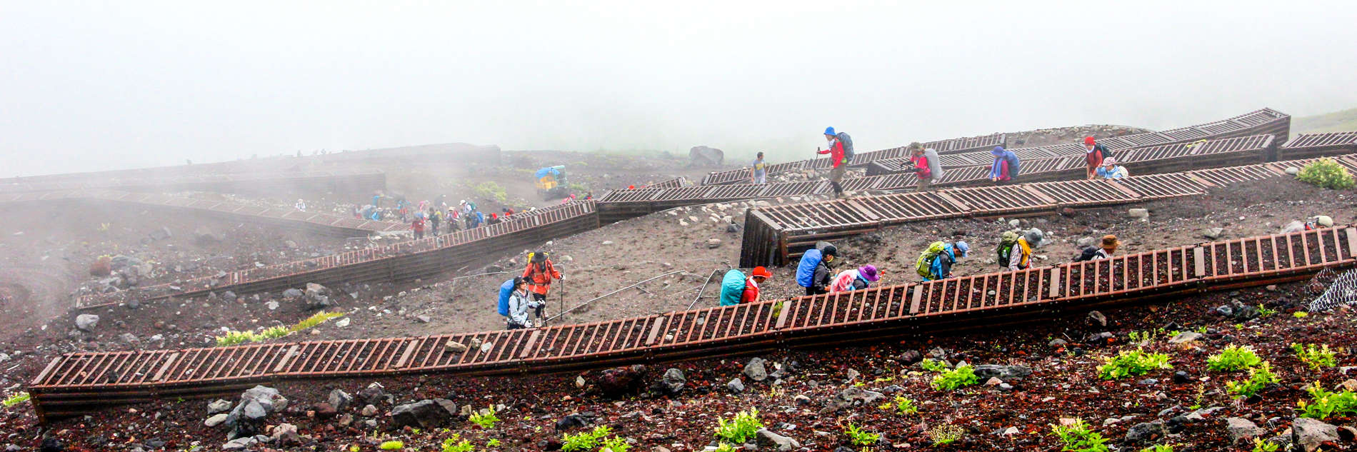 Hikers in colourful clothing on the zigzag mountain path of the Fuji Yoshida trail.