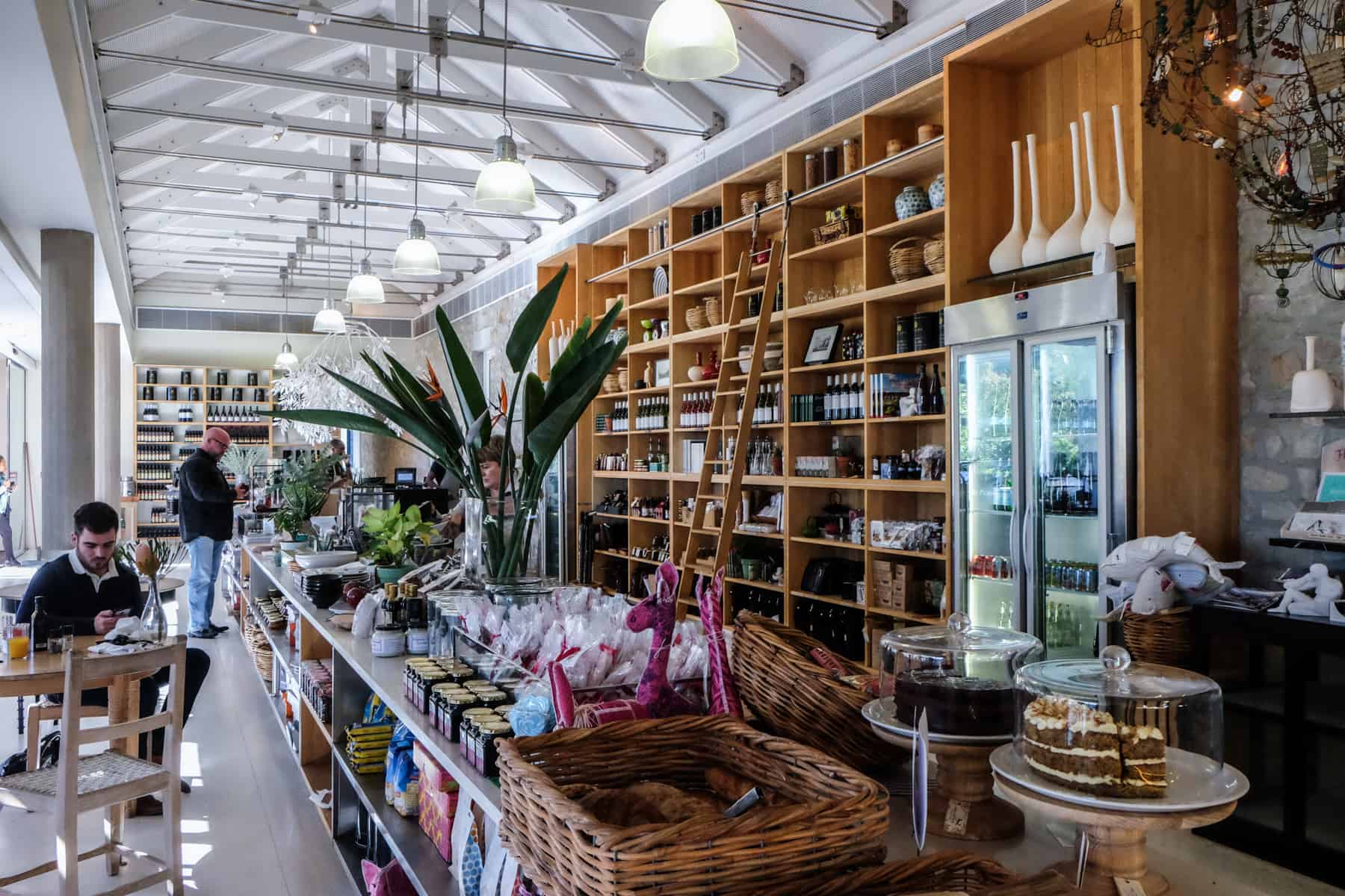 A long modern white cafe interior half filled with golden wooden shelving lining the wall at Cafe Tokara Vineyard Stellenbosch 