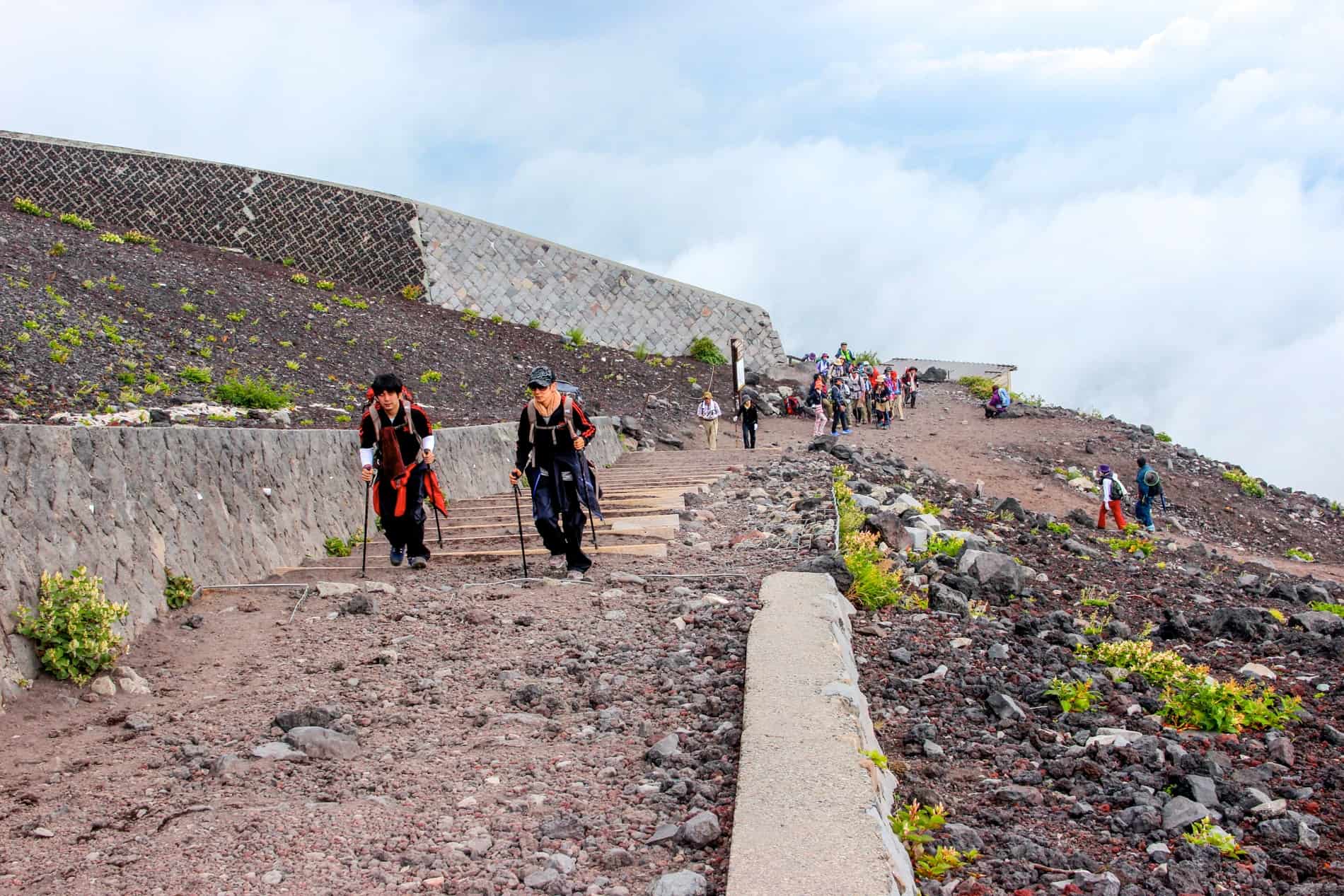 Hikers on a steep and rocky incline while climbing Mt. Fuji. 