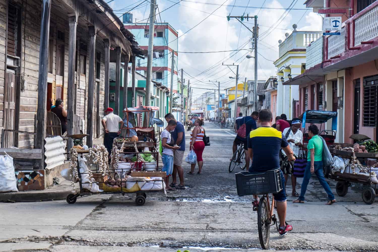 Small market stalls on a neighbourhood street in Camagüey, Cuba lined with colourful painted buildings. 