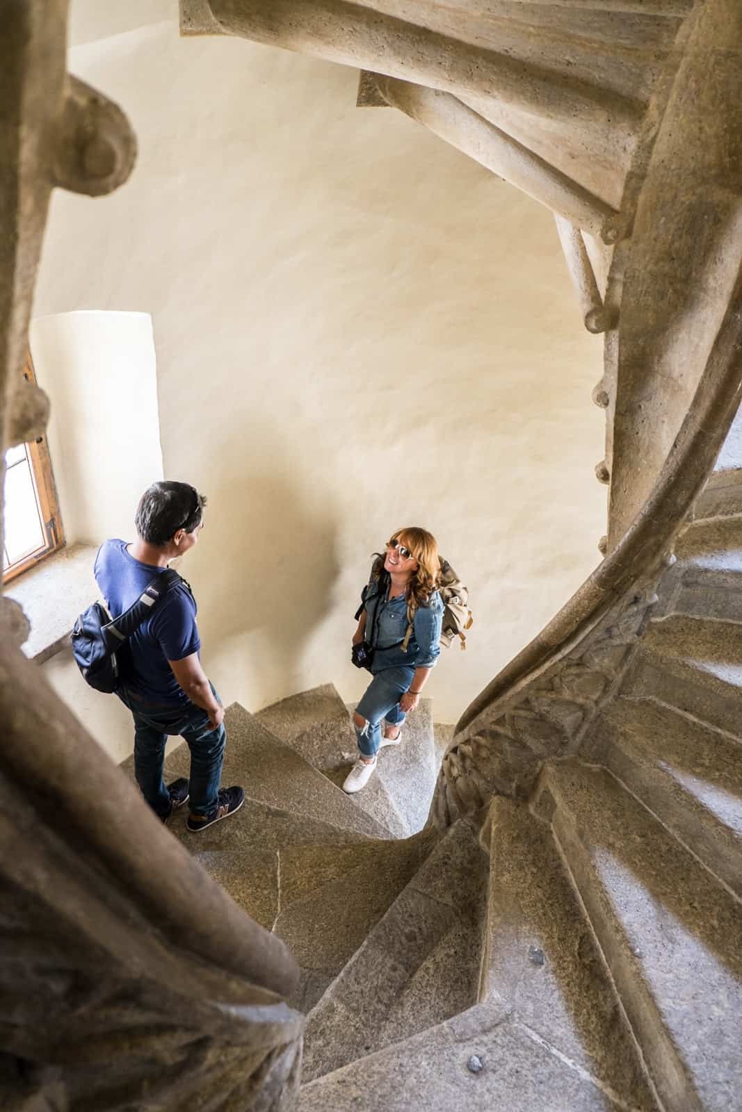 A man and woman meet on the stone steps of the double spiral staircase in Graz, Austria.