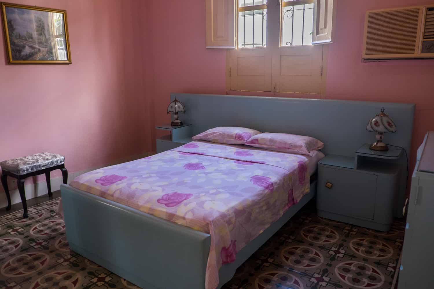 A pink walled bedroom with blue furniture at a Casa accommodation in Cuba.