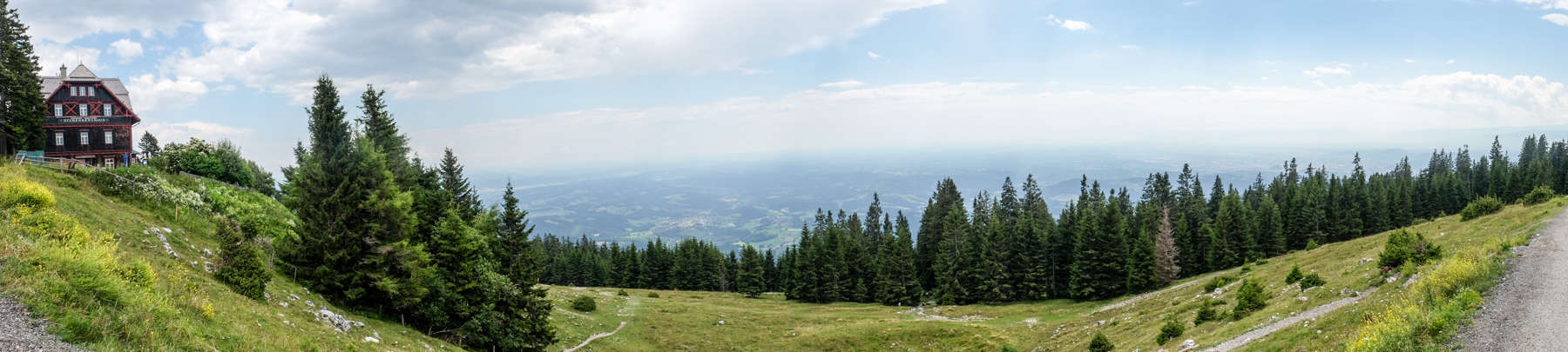 A panoramic view from the top of the Schöckl Mountain near Graz, Austria showing the mountain hut, a wide view of neighbouring countries and part of the hiking pathway
