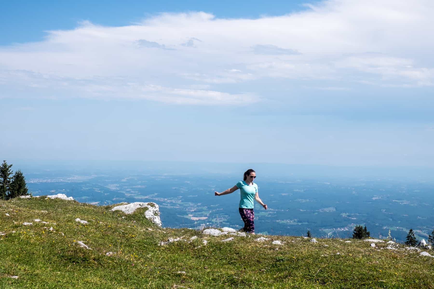 A woman walking along the stoney and grassy summit of Schöckl Mountain, Graz