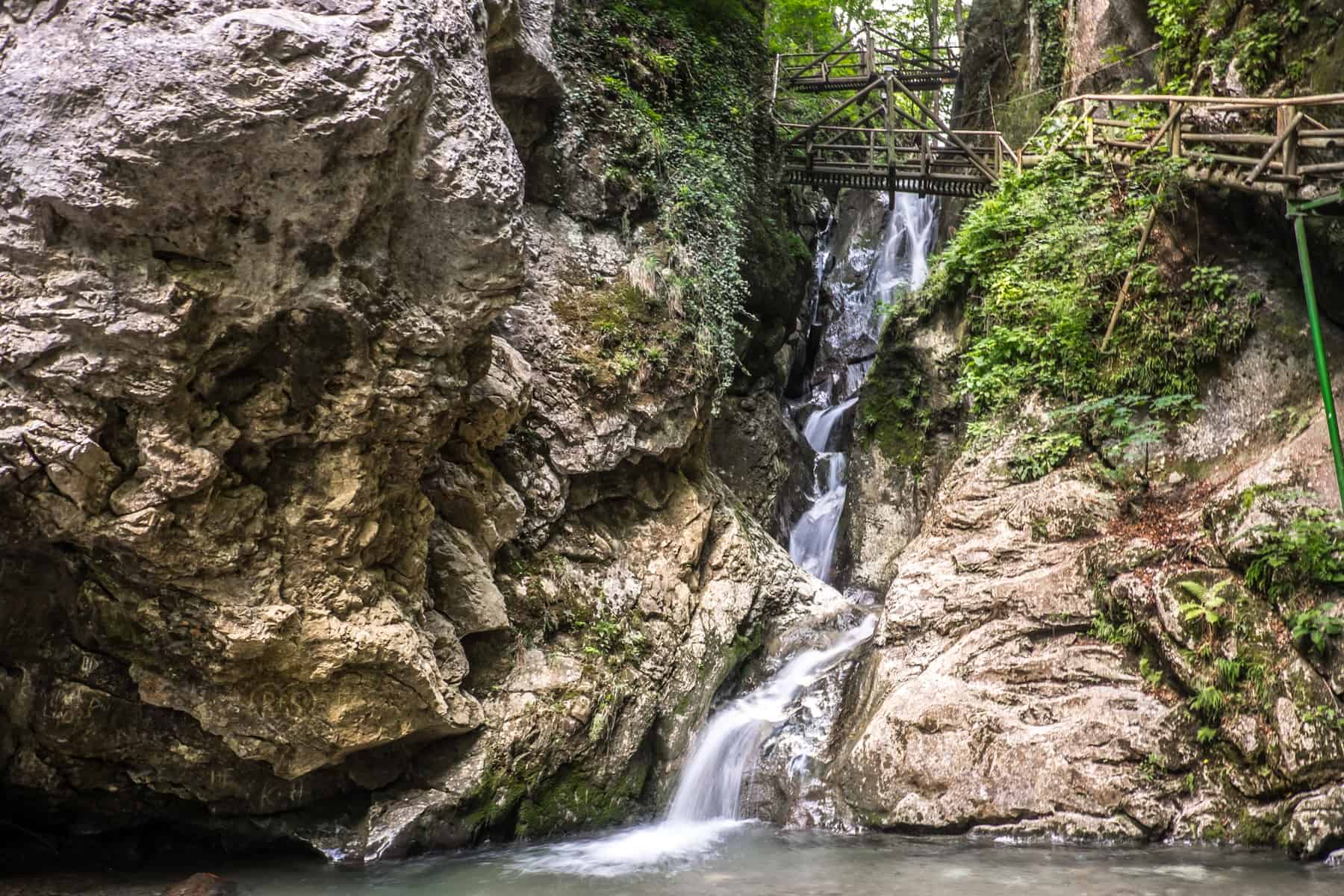 The white waterfall called Kesselfall runs betweens two brown rock faces in the Kesselfallklamm gorge in Graz, Austria