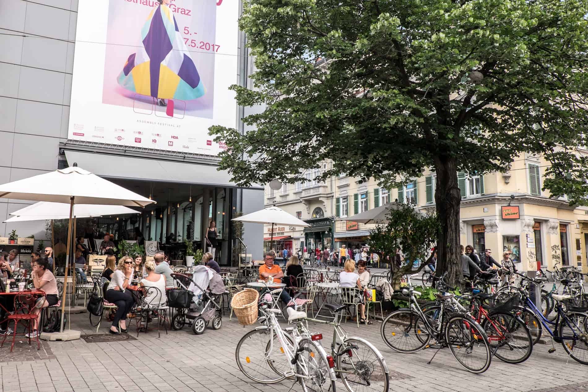 People eat outside in the modern area of Graz city, Austria.