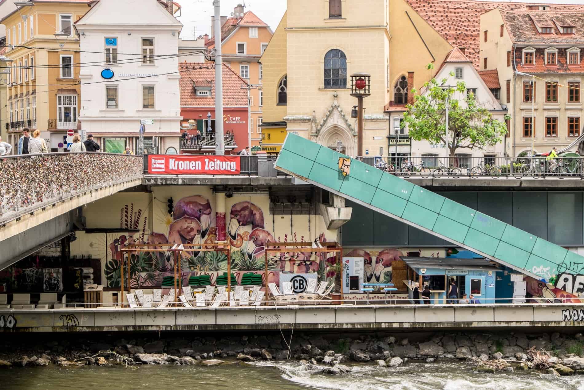 A bar with street art under a bridge across the Mur River in Graz, Austria