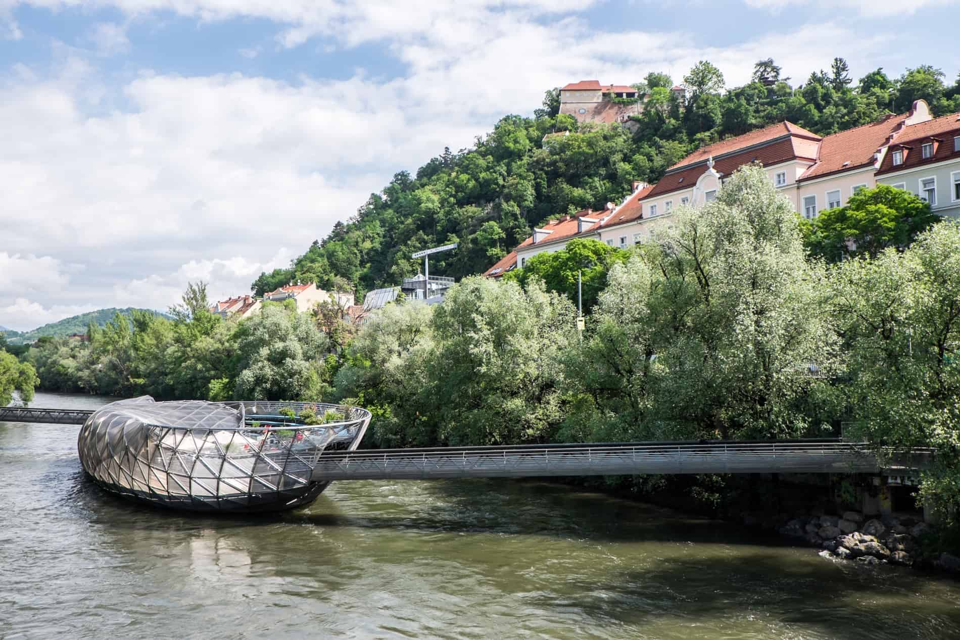 The steel and glass Murinsel café and exhibition space sitting in the middle of the Mur River in Graz, Austria.