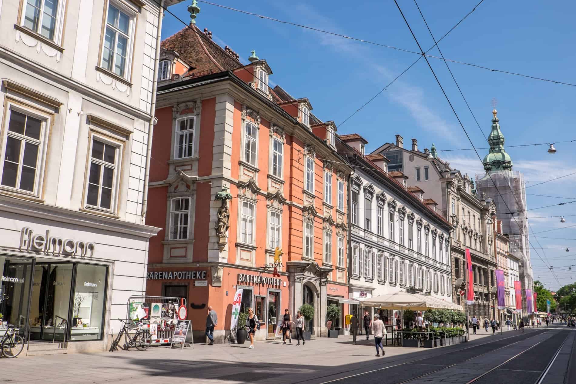 Orange and mocha hued buildings line the busy Herrengasse street in Graz, Austria.