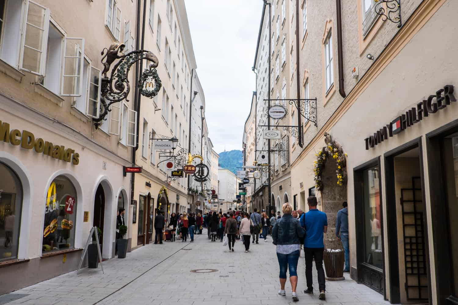 People walking down Getreidegasse - a shopping street in Salzburg known for its pretty, stylish signage. 