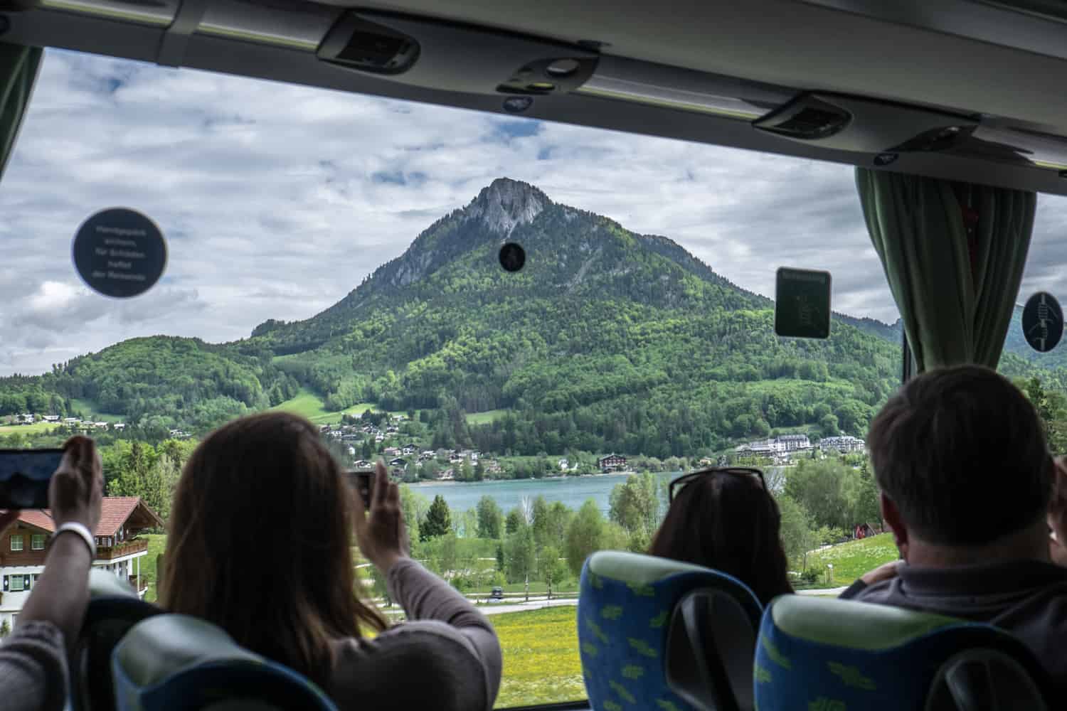 People on the Sound of Music tour bus taking pictures of the hills and mountains of Salzburg through the bus window. 
