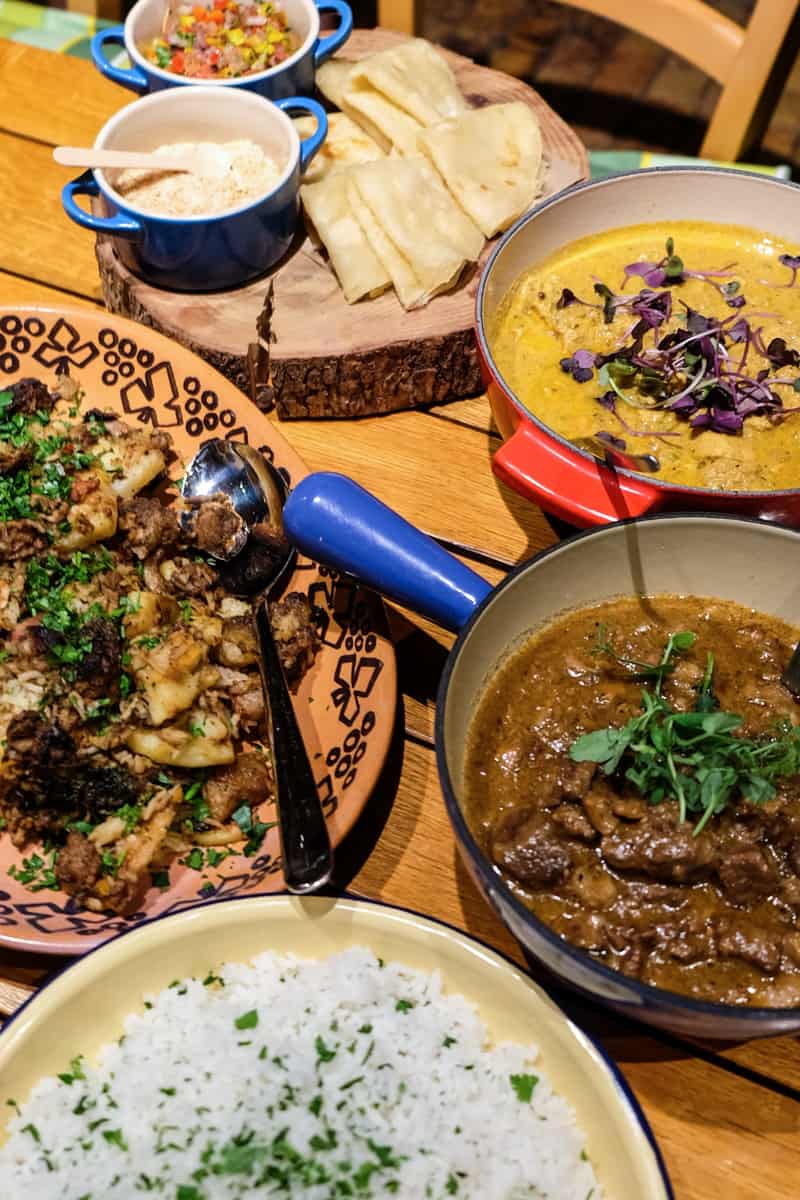 Four round dishes of curries and sauces and a plate with tortilla bread - a display of the colourful braai cuisine found in South Africa