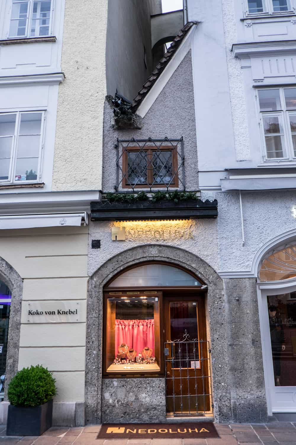 A narrow, 1.4 metre wide grey stone building with a jewellery shop front is wedged between two larger buildings. It is the smallest house in Salzburg. 