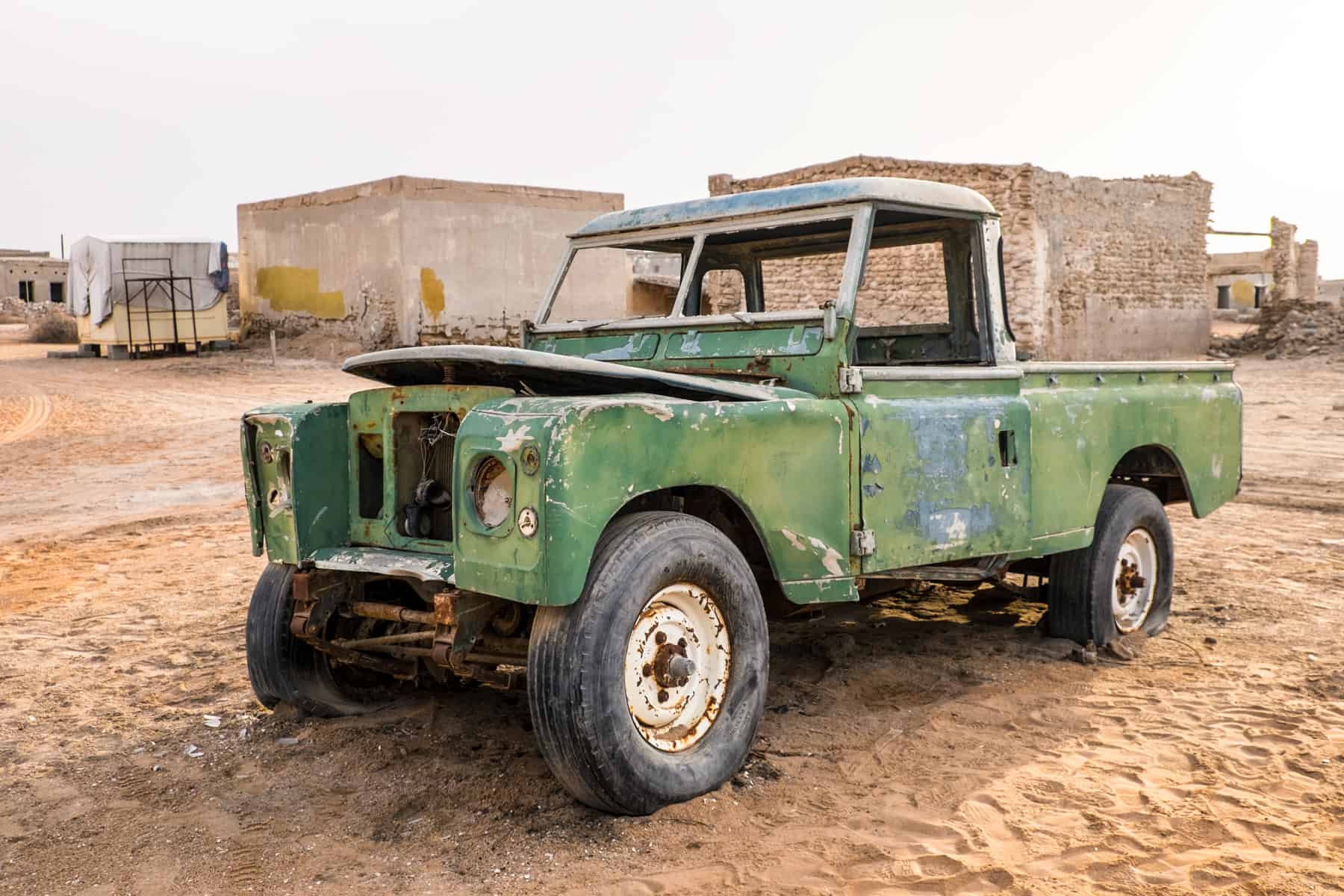 A dark green truck, left abandoned in the orange coated ghost town of Al Jazirat Al Hamra in Ras Al Khaimah 