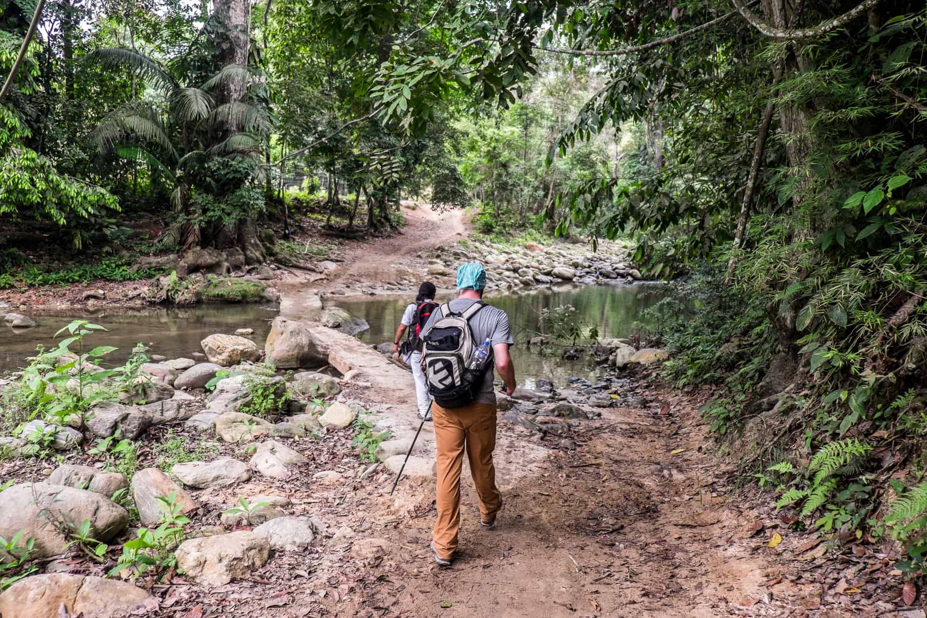 An indigenous guide and a trekker at a river crossing on Colombia Lost City Trek. 