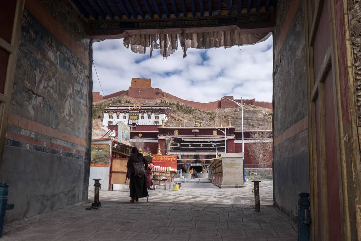 The view of the layered white and red buildings of the Palcho Monastery in Gyantse, Tibet as seen from the entrance doorway