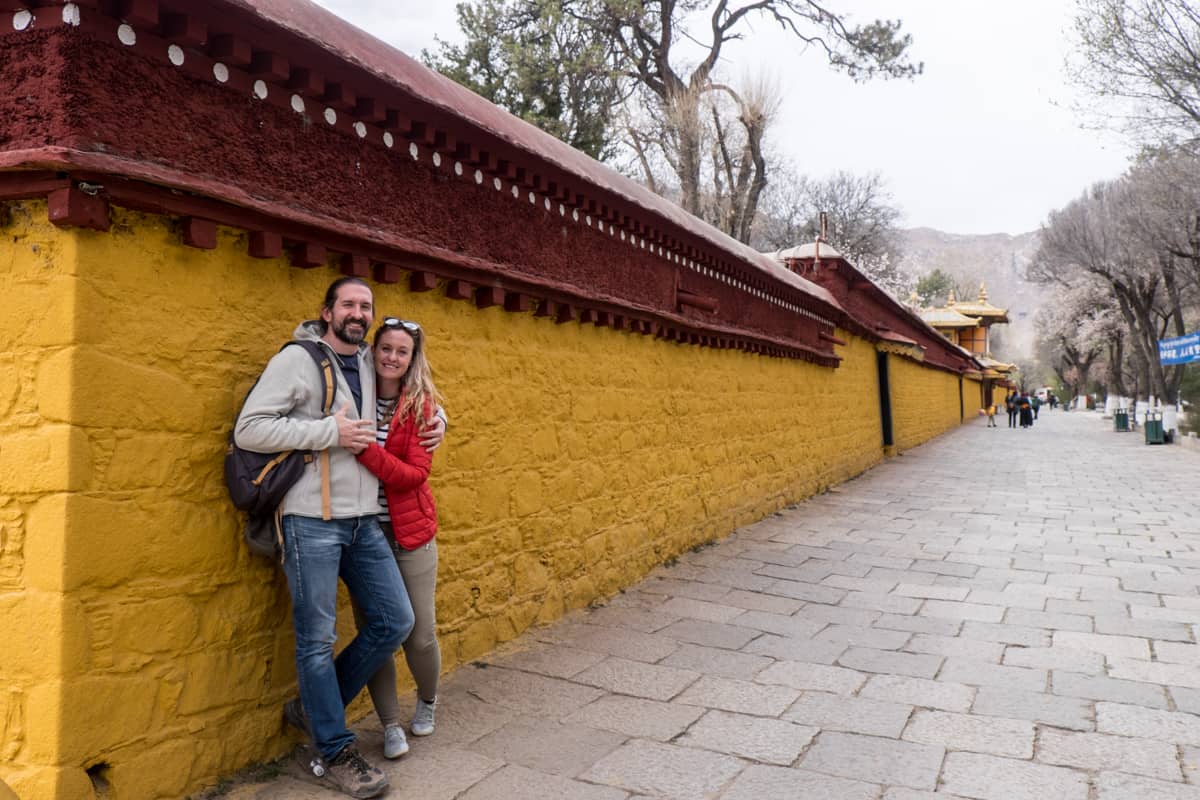 A couple pose against the distinctive yellow wall that surrounds the Norbulingka Summer Palace in Lhasa Tibet