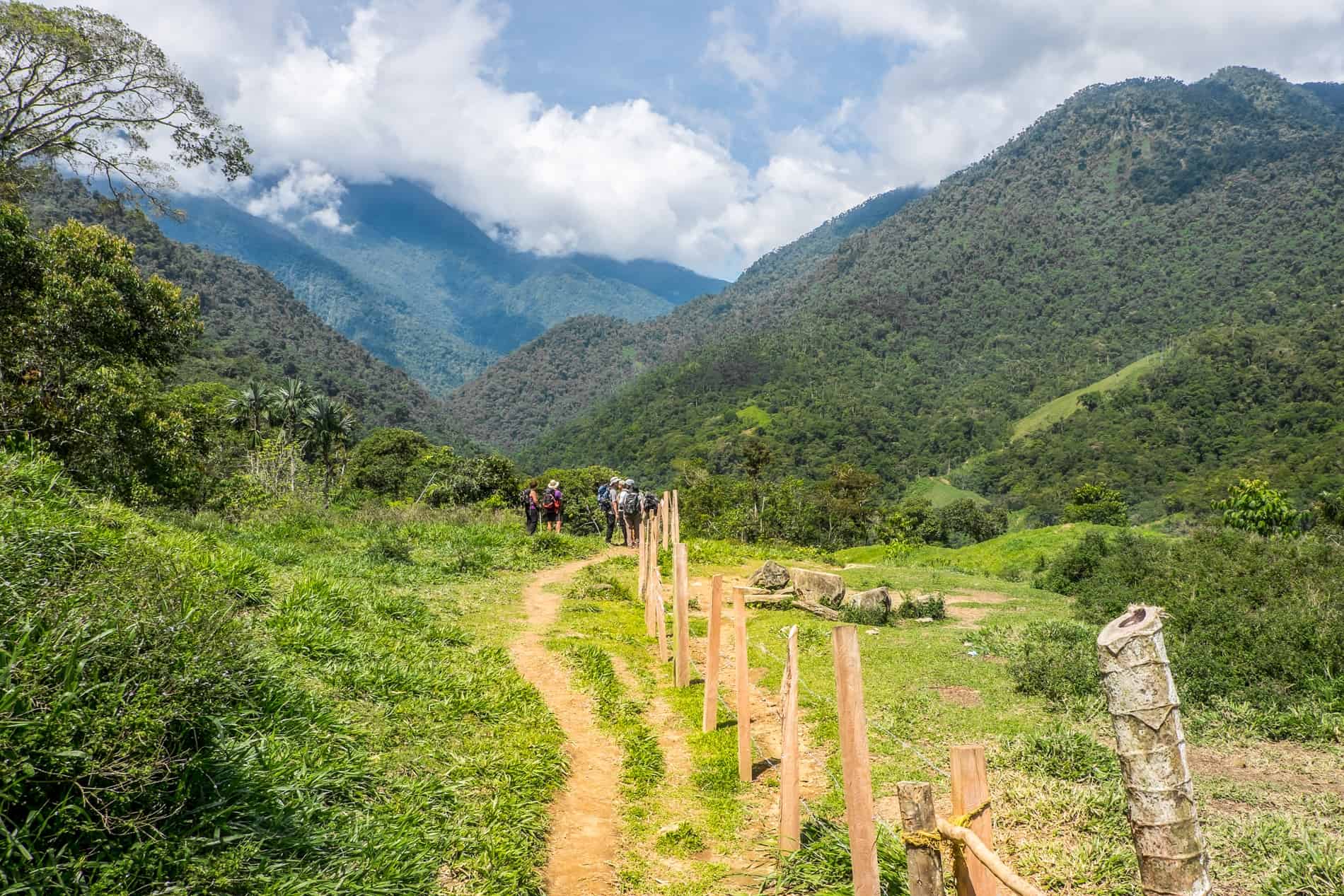 A small group trekking through hills and farmland on the Lost City trek in Colombia