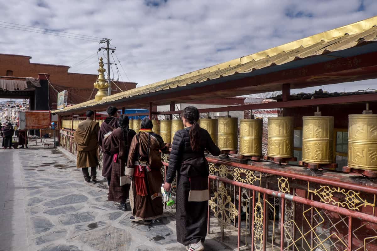 Four Tibetans spin golden prayer wheels in a clockwise direction at the Palcho Monastary in Gyantse, Tibet