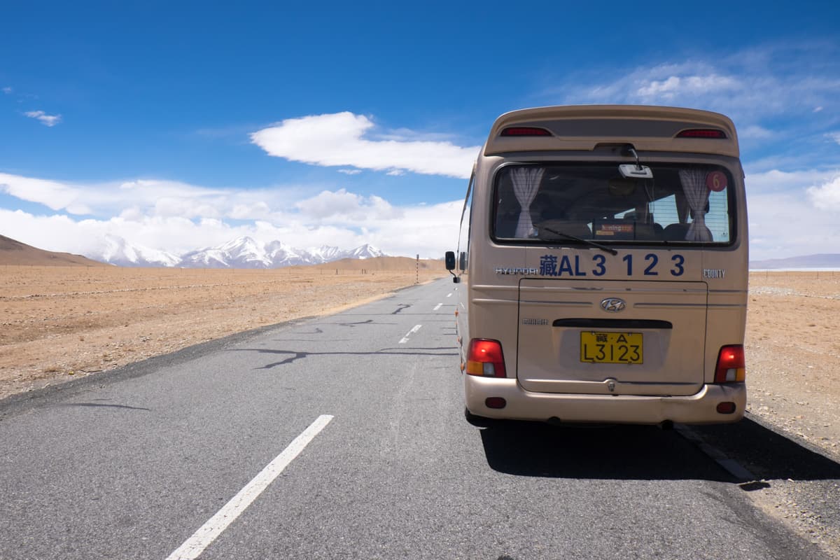 A private light-gold tourist bus parked on the side of a high road in Tibet as part of an organised tour