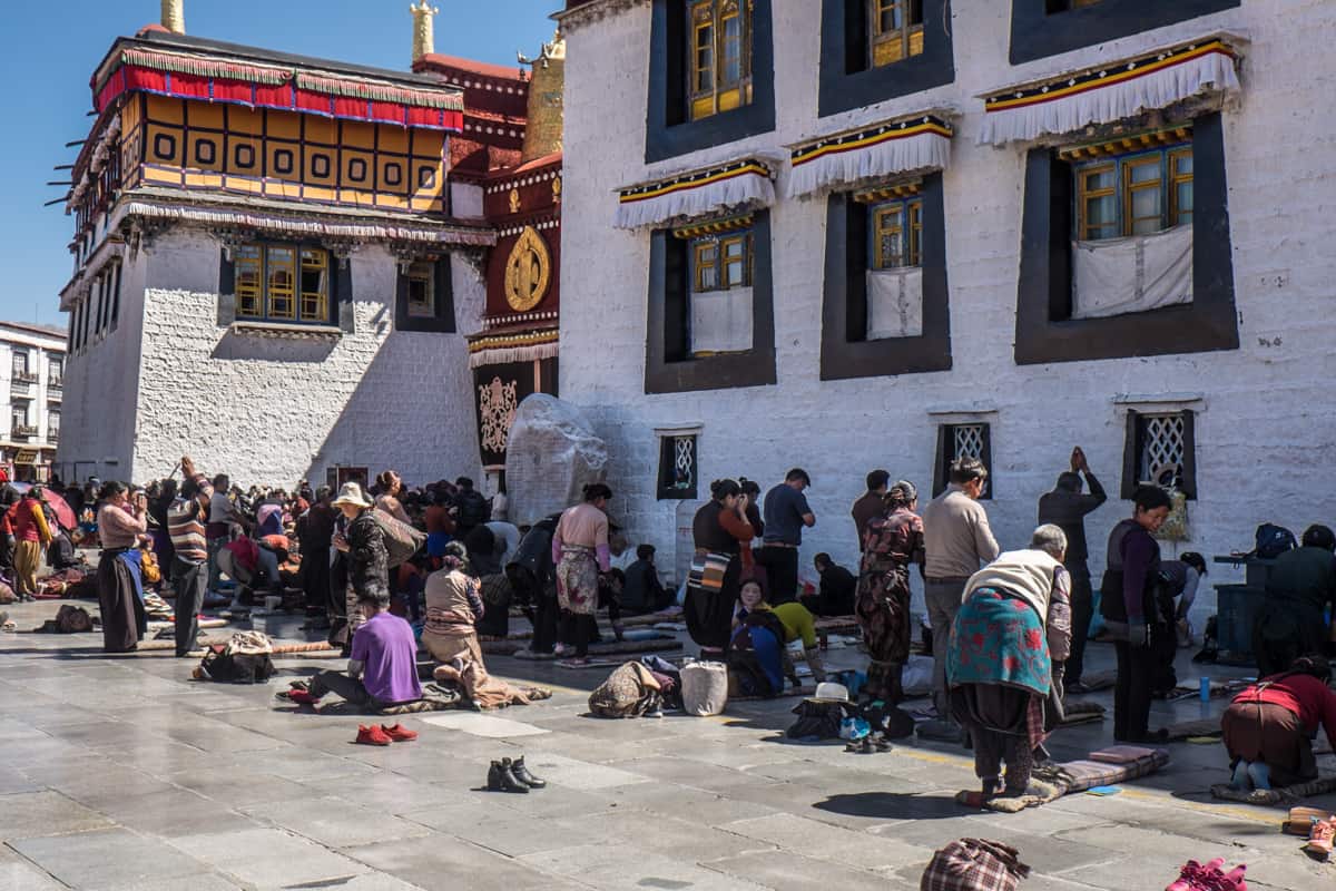 Praying Tibetans on the floor outside the main entrance of the white stone Jokhang Temple