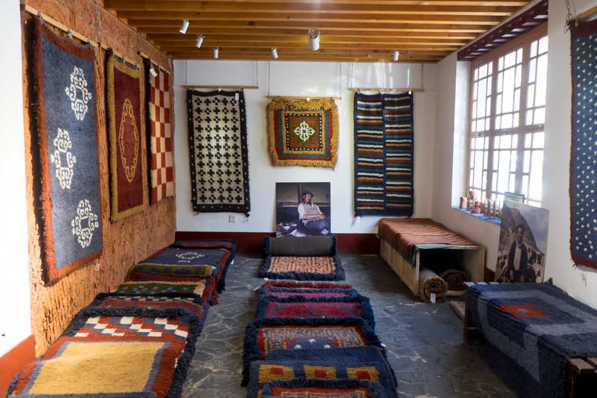 Rugs and handicrafts on show in a Tibetan owned shop in Lhasa. A picture of a local man rests on the bottom of the back wall.