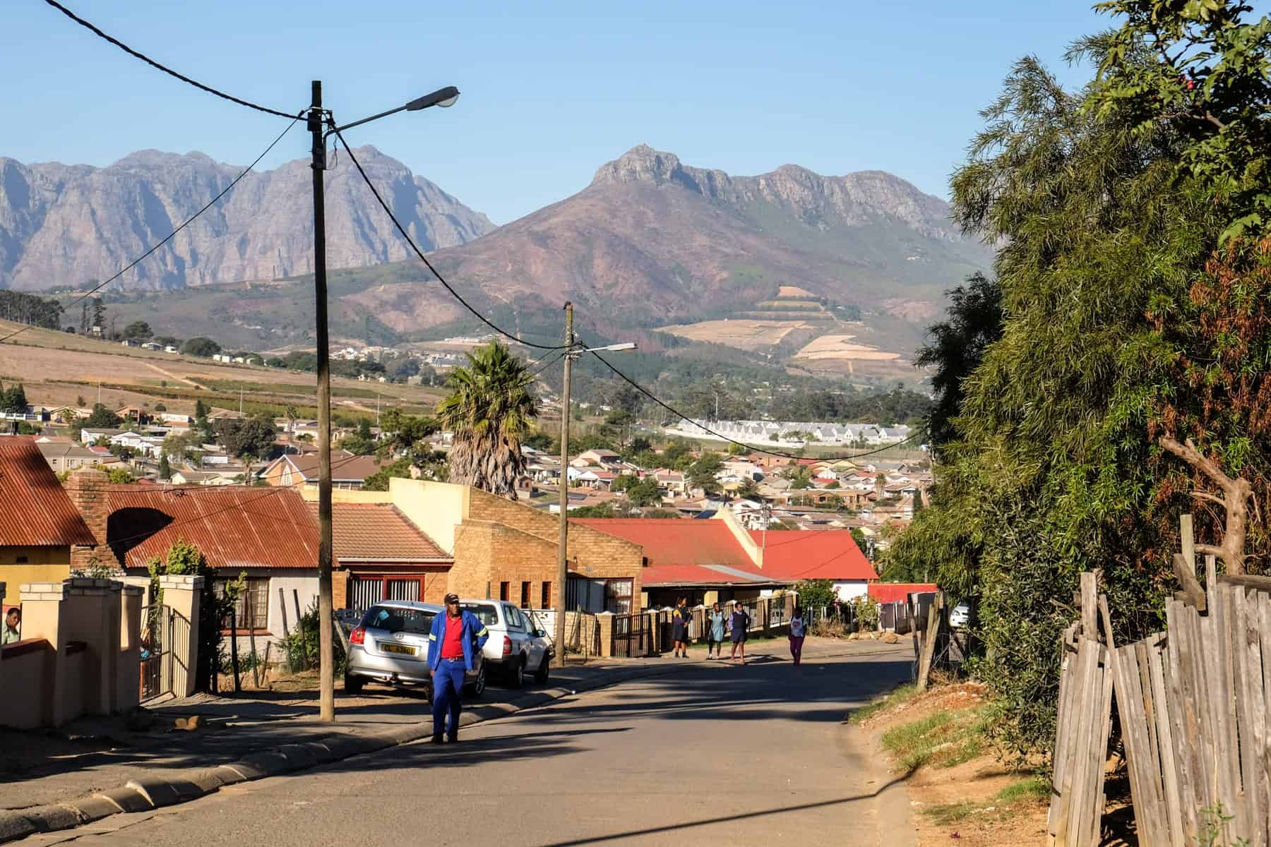 Looking out past the low-rise orange buildings Township of Kayamandi in South Africa, backed by a brown mountainous plateau