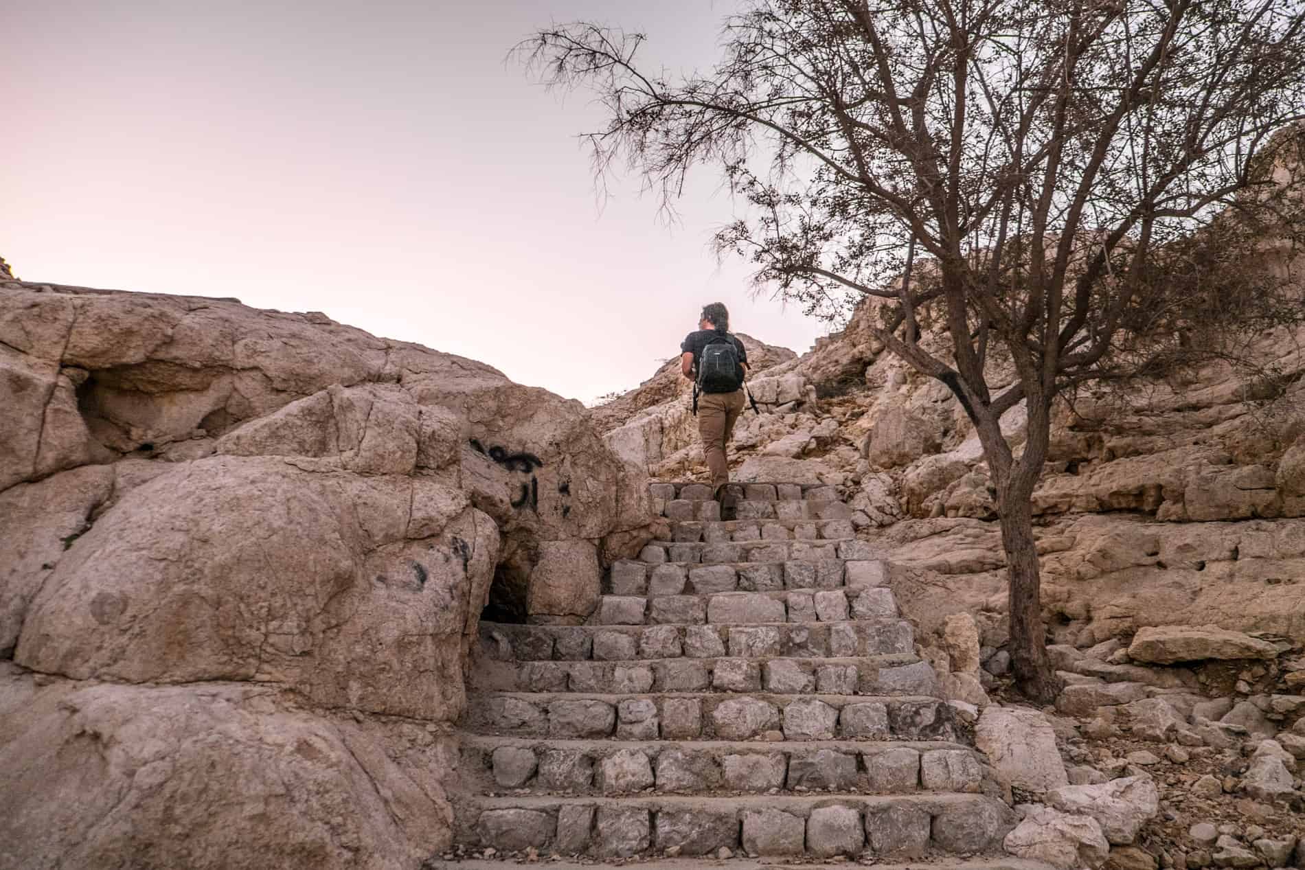 A man walks up the stone steps on a sandy mountain top in Ras Al Khaimah. 