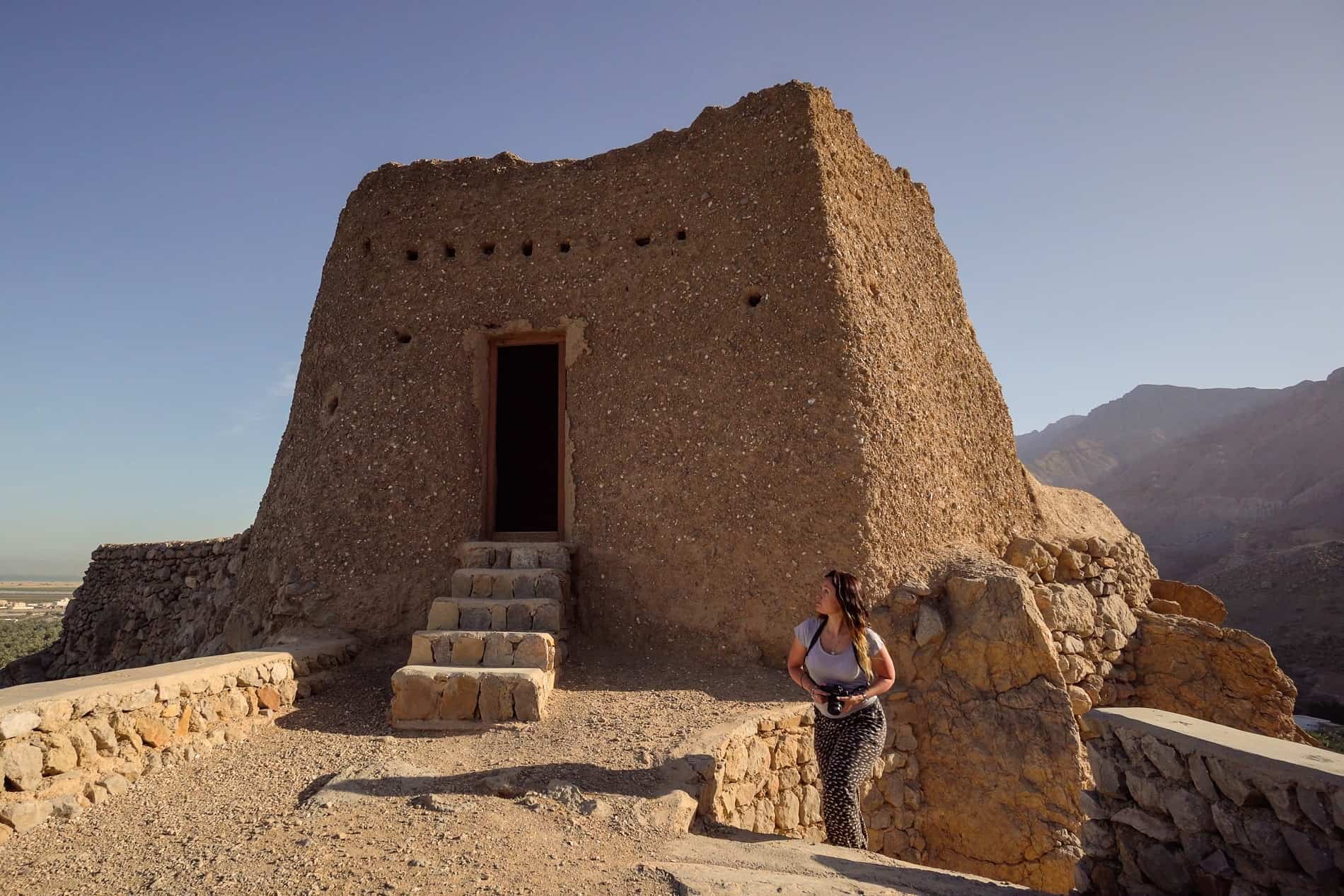 A woman walks up the stairs to the top of a sandy, mud fortress in the Jebel Jais mountains in the UAE.